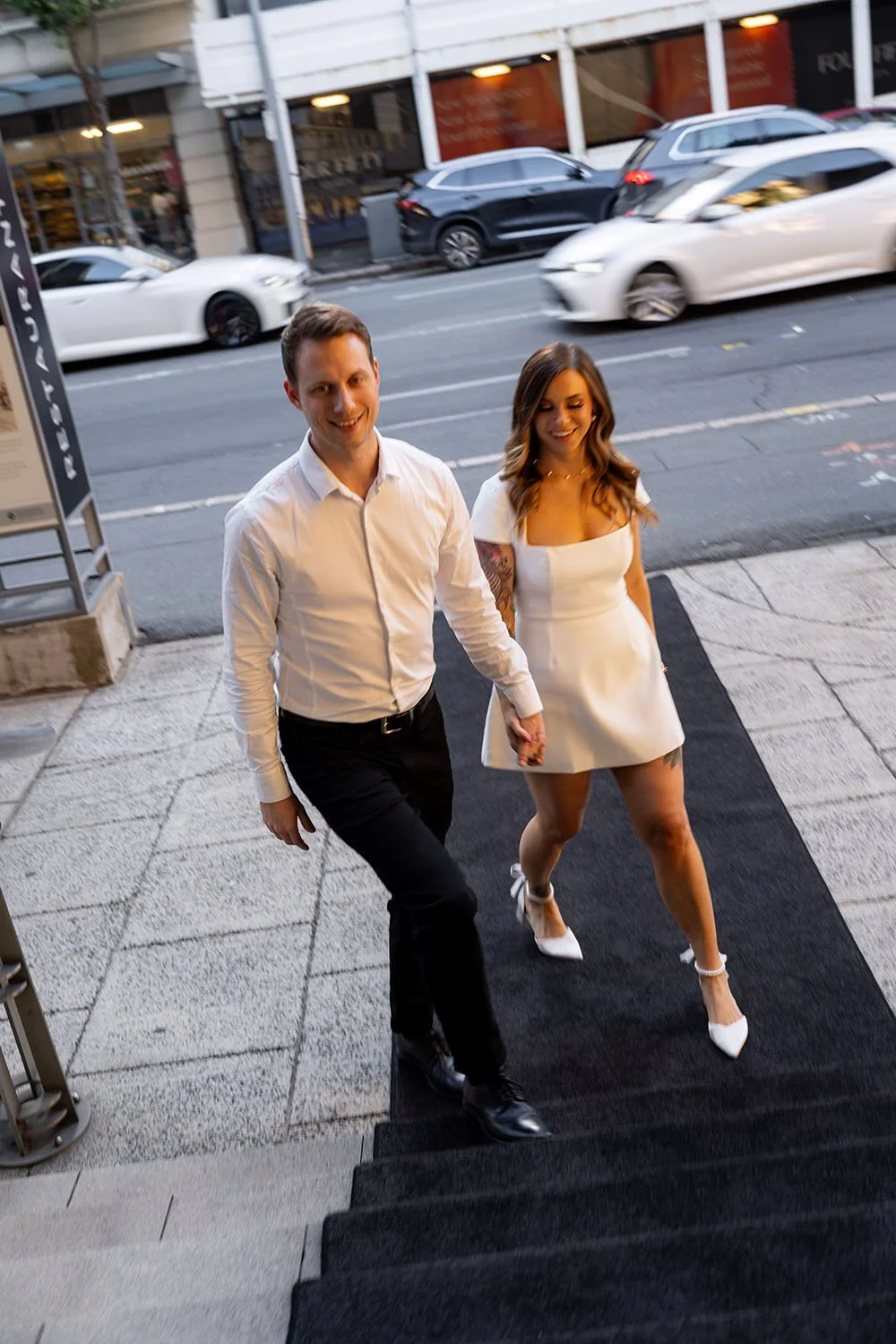 Morgan holding Brenna's hands walking on a black carpet