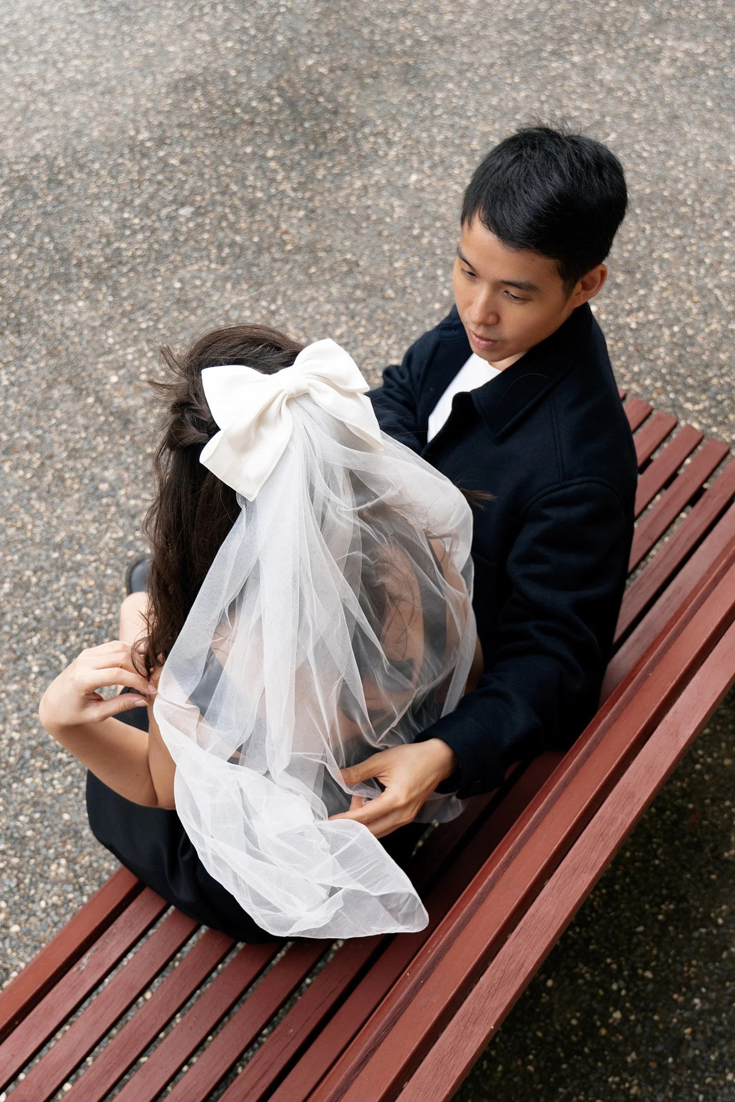 Paul and Krystel sitting on the bench and Paul try to adjust Krystel' veil