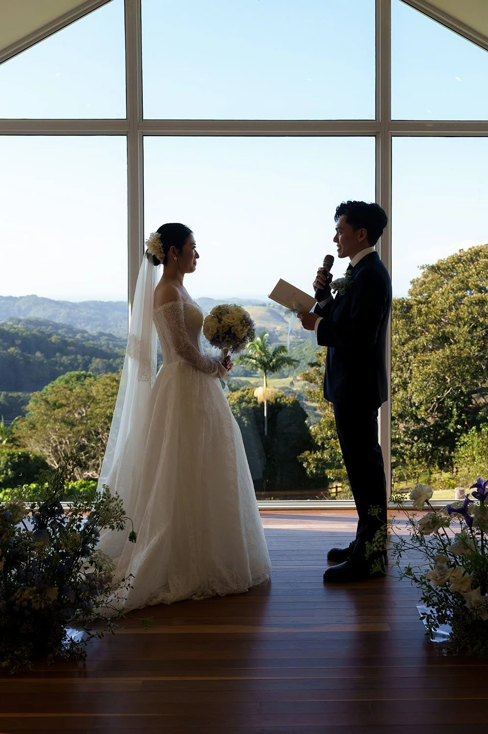 Michael holding a mic reading his vow and Lisa stand facing to him