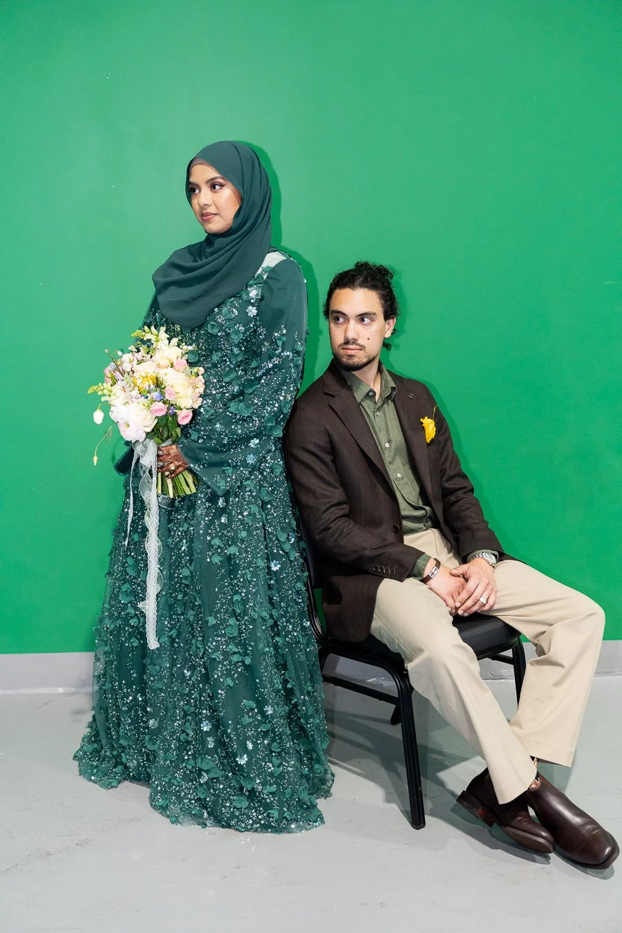 Junaid seating and Afifah standing next to him, and they both look to the same direction