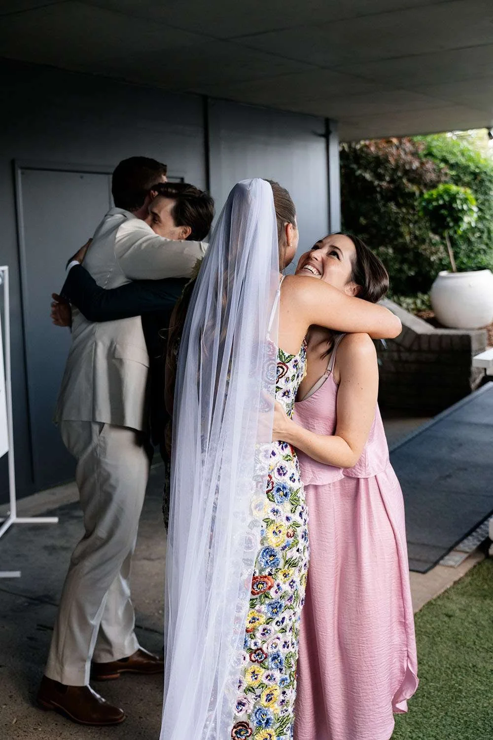 bride and groom hugging their guest