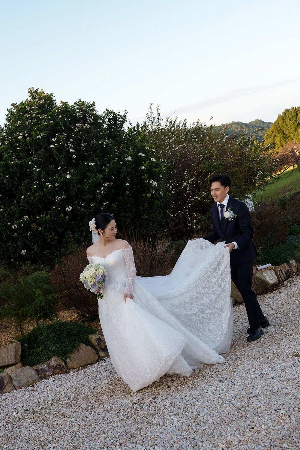 Michael holding up Lisa's wedding trail walk together and Lisa look back to him 