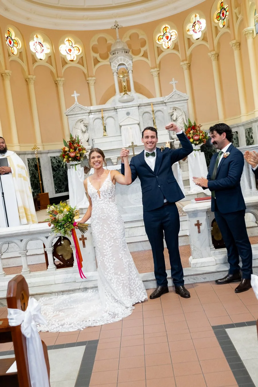groom Giordan raising his hand while holding Sonya's hand and they both smell to the camera
