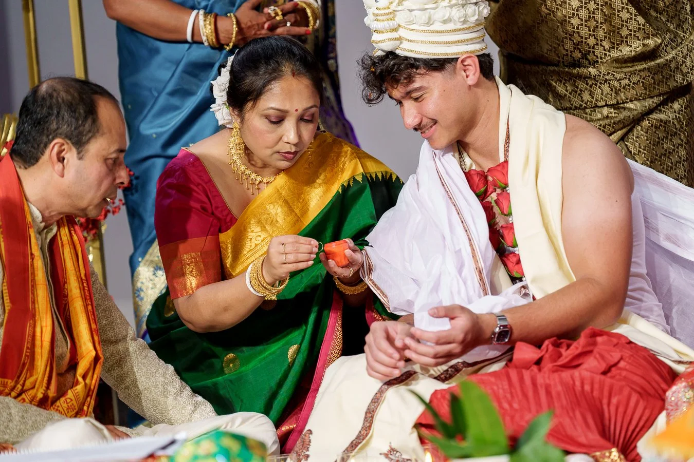 Casey holding the wedding ring with red colour on it, calms Amrita's hair and unties guiding them to do so