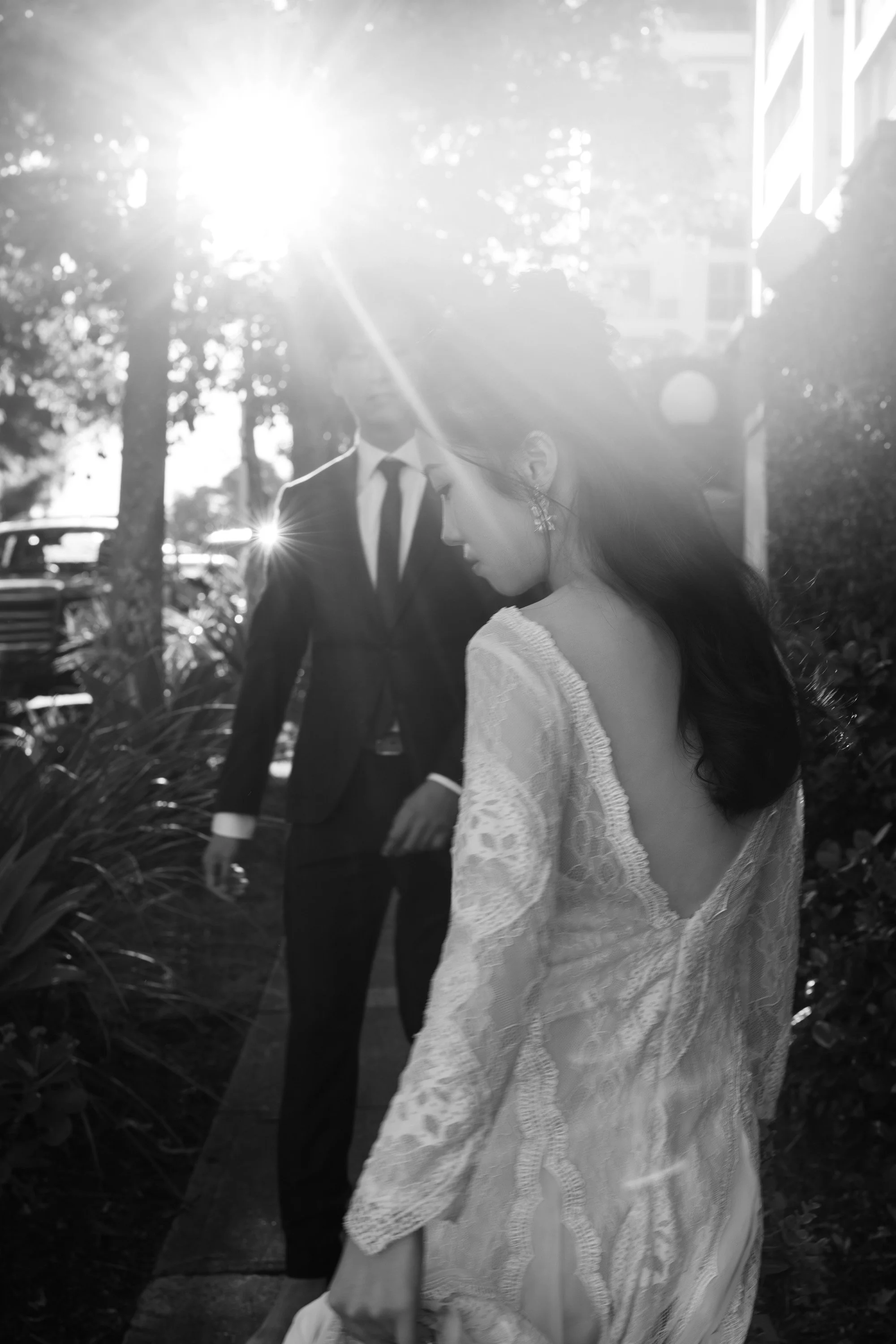 bride Cassie look at her right side floor and groom Leo look at under a sunlight on the street near Wilson Outlook Reserve