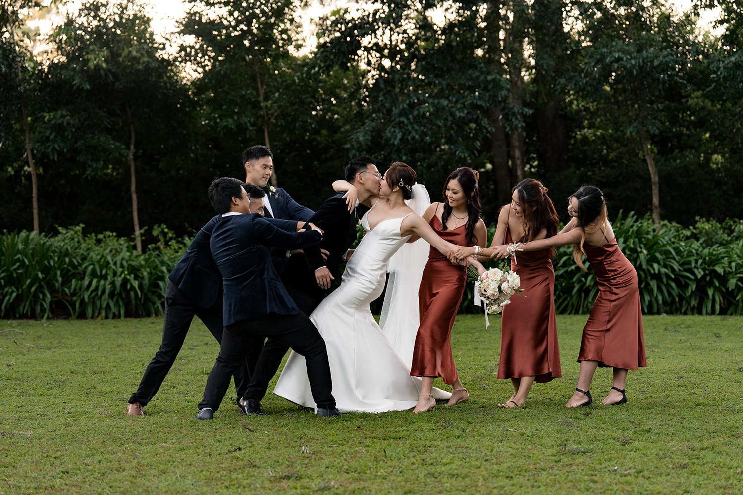 bride Vicky and groom Brus kissing and bridal party try to pull them apart in Gabbinbar Homestead