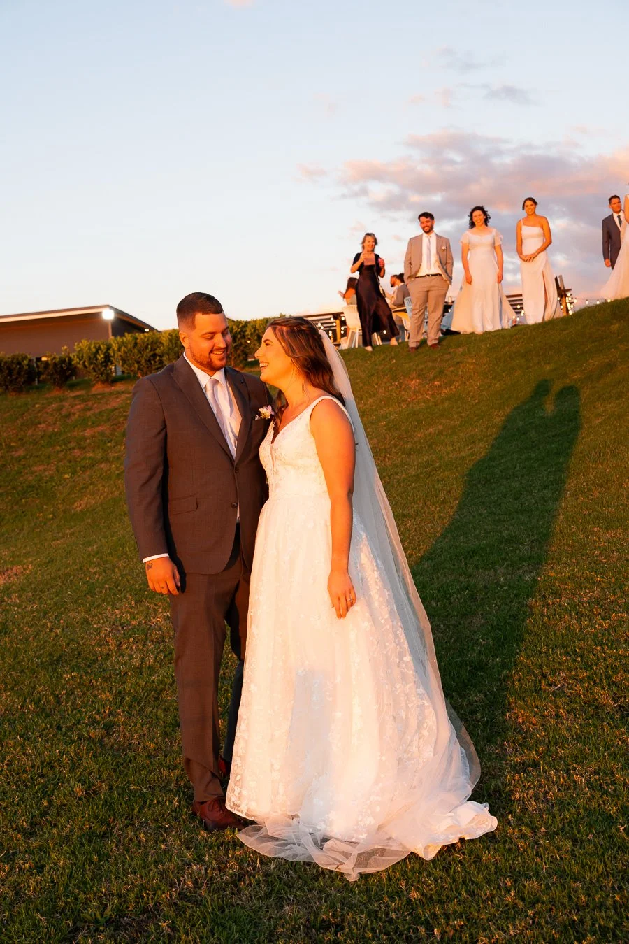 Chiarra and Ben stand next to each other laughing with sunset on their face