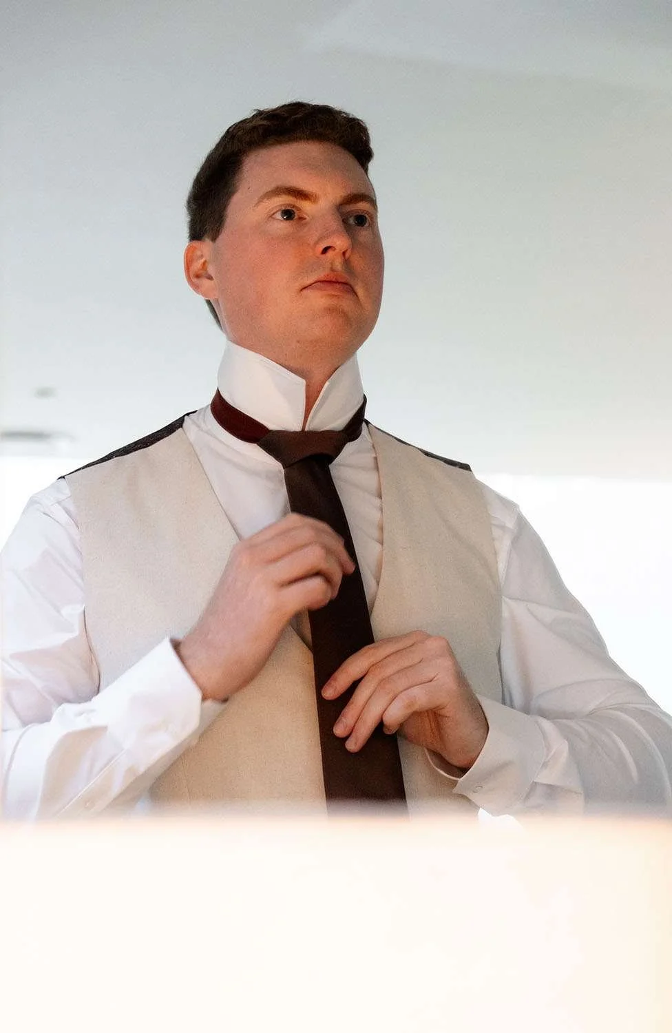 The groom Jack stood in front of the mirror, tying his tie