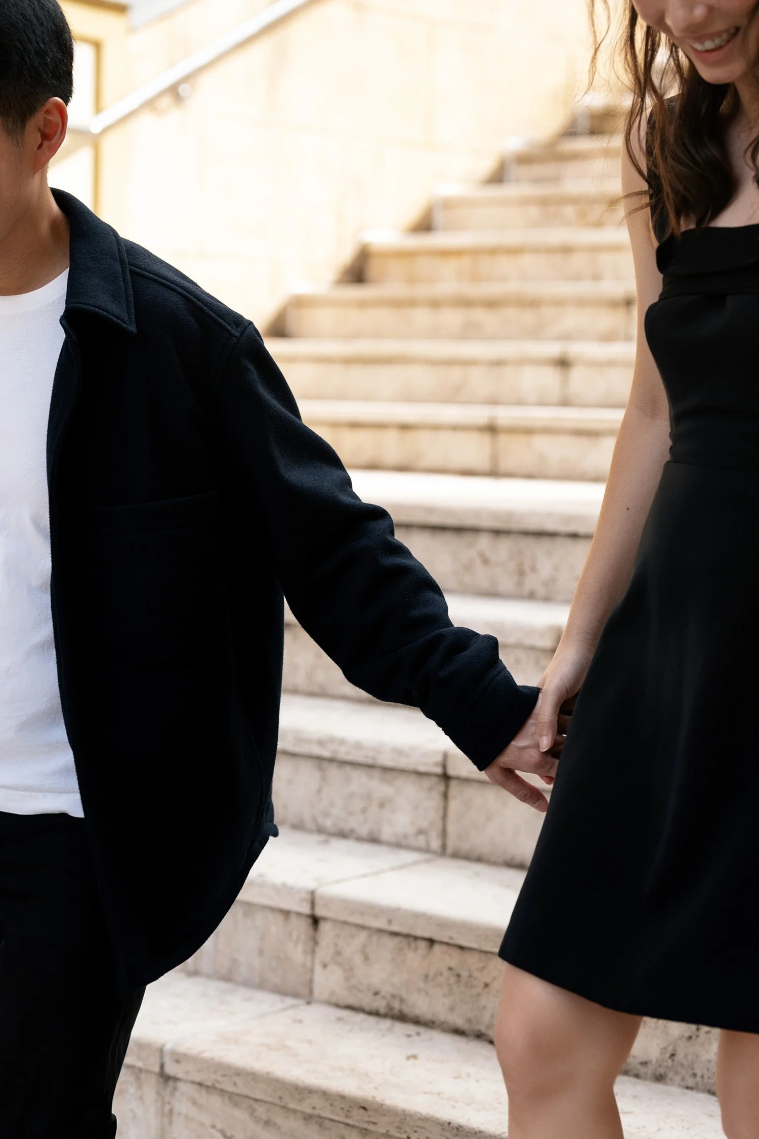 Paul and Krystel holding hands walking down the stairs with big laugh