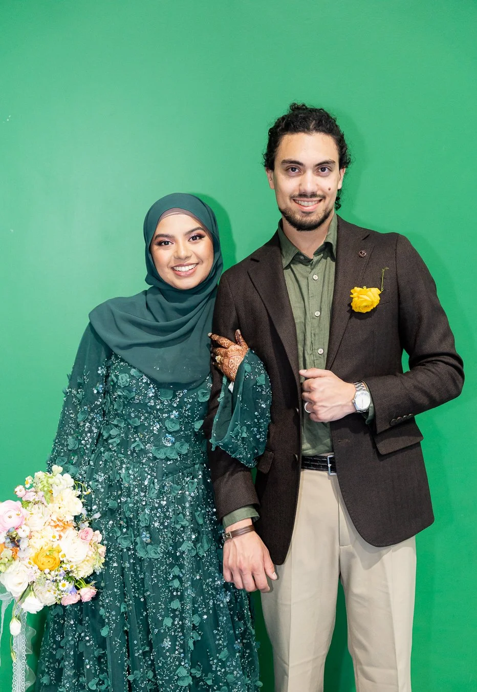 Afifah holding Junaid's arm and they both look at the camera