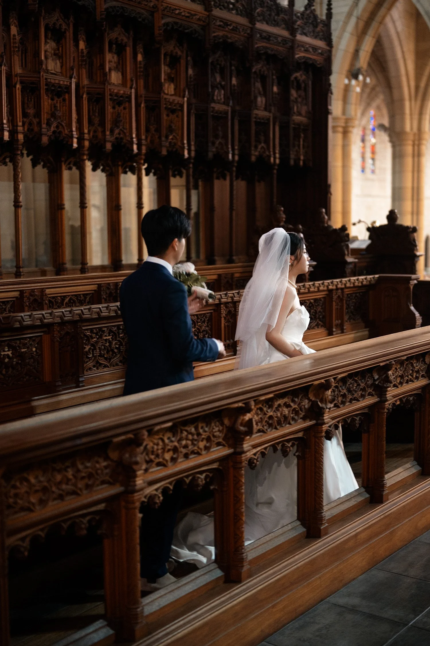bride and groom walk together behind the wooden railling in St John's Cathedral in Brisbane