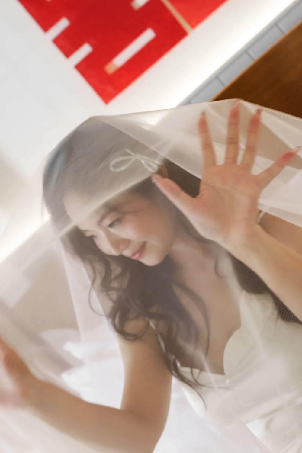 A woman smiling and pressing her hand against a sheer plastic cover over her face.