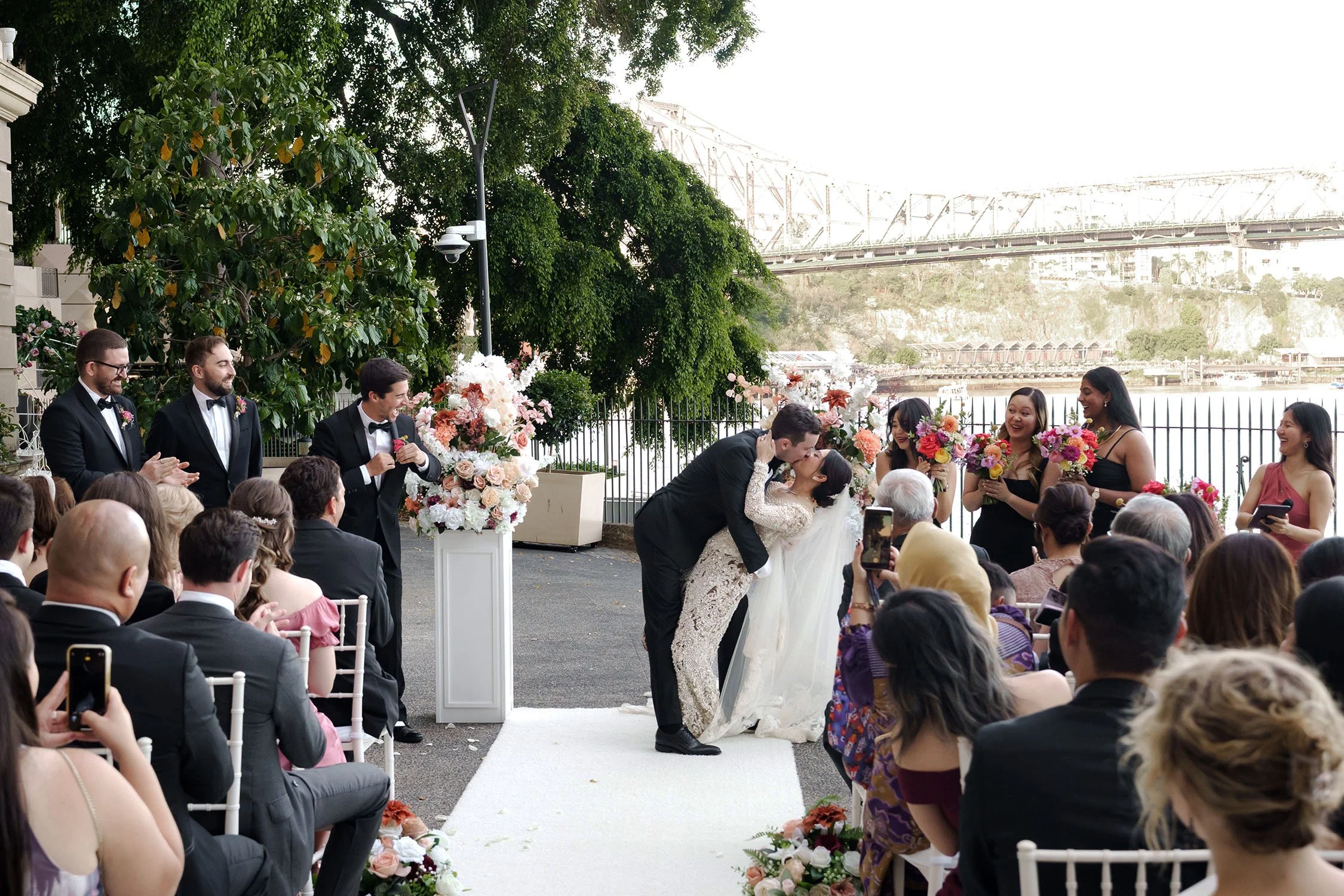 groom Cliffe dipping kiss bride Nori in their wedding ceremony and everyone cheers for them in Customs House Brisbane, wedding package for them