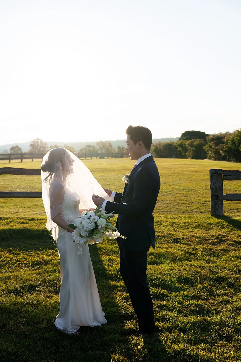 groom Eric holding Flora's veil while look at her and made her laughing