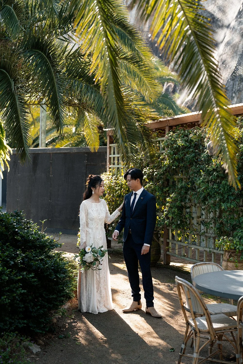 bride Cassie touching groom Leo's shoulder near some green trees in Wilson Outlook Reserve