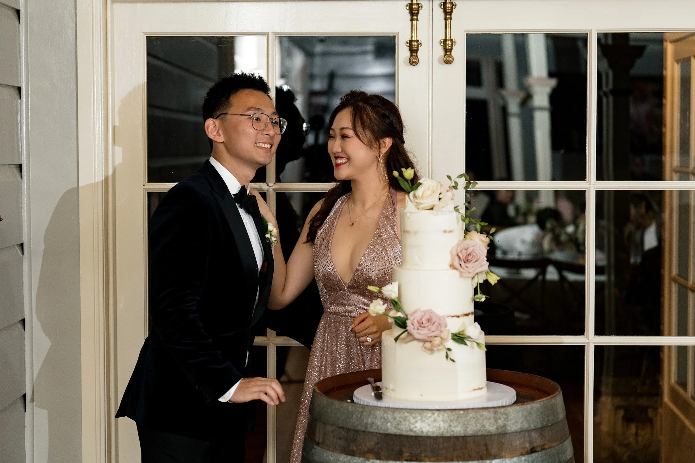 bride and groom stand behind the wedding cake in reception