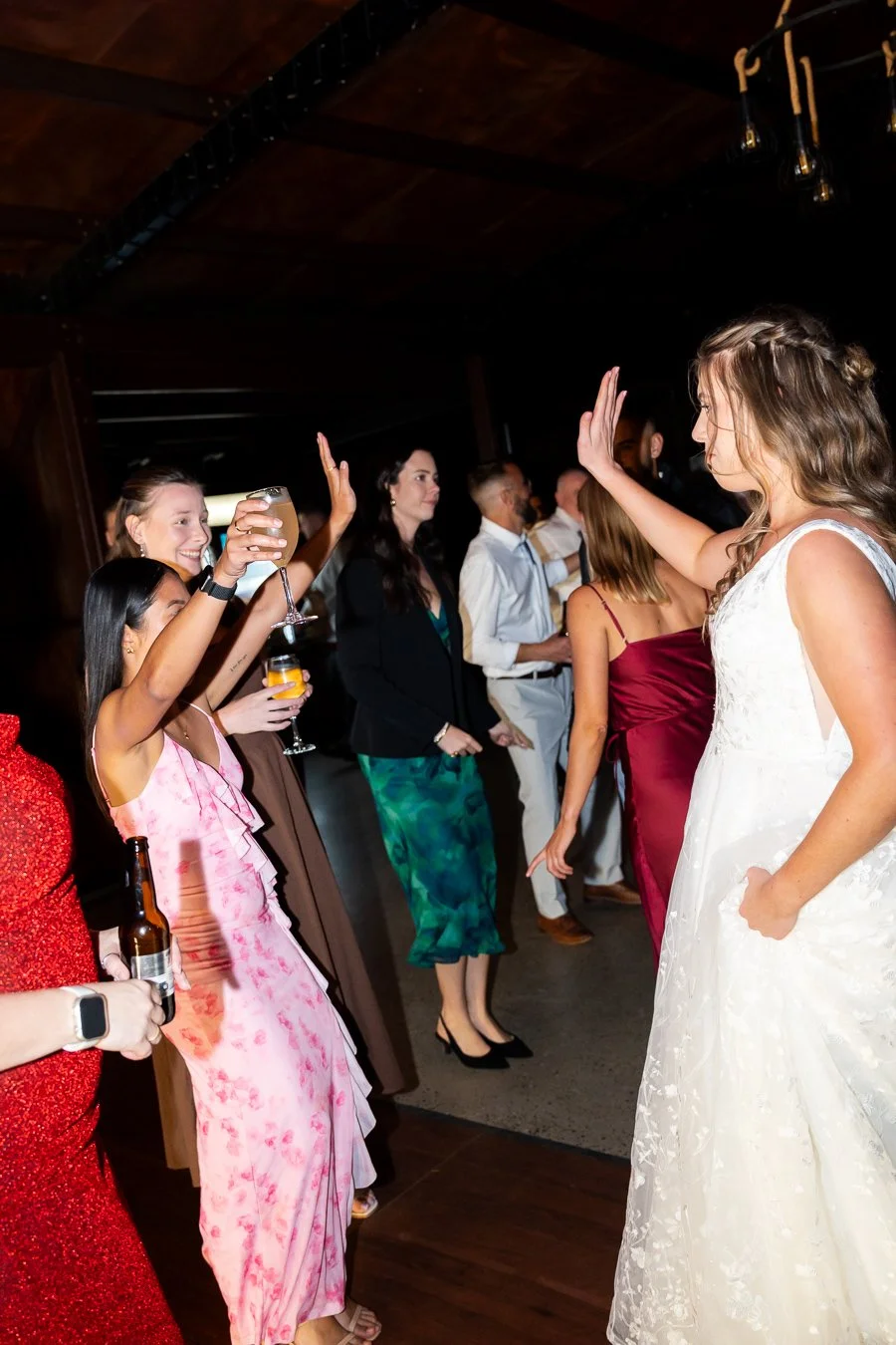 bride Chiarra hand up celebrate with two female guests in dace floor