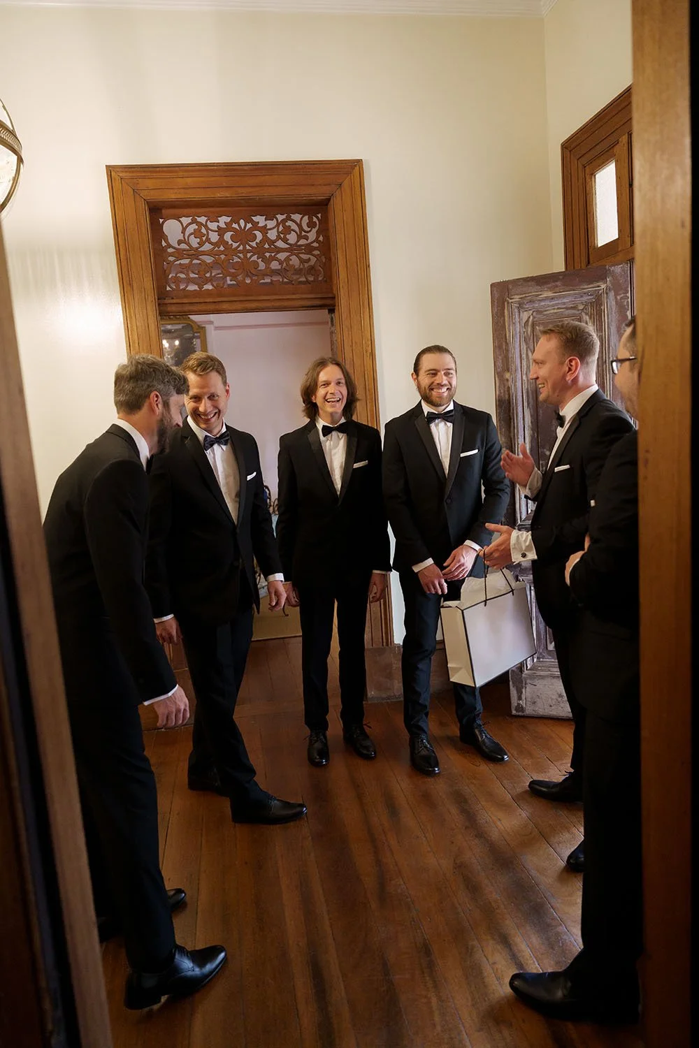 Morgan laughing to his groomsmen while they all standing in the front door