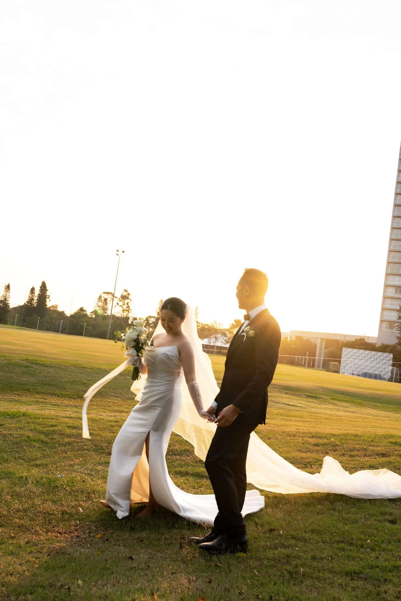 bride Wendy and groom Alex holding hands walking together on grass