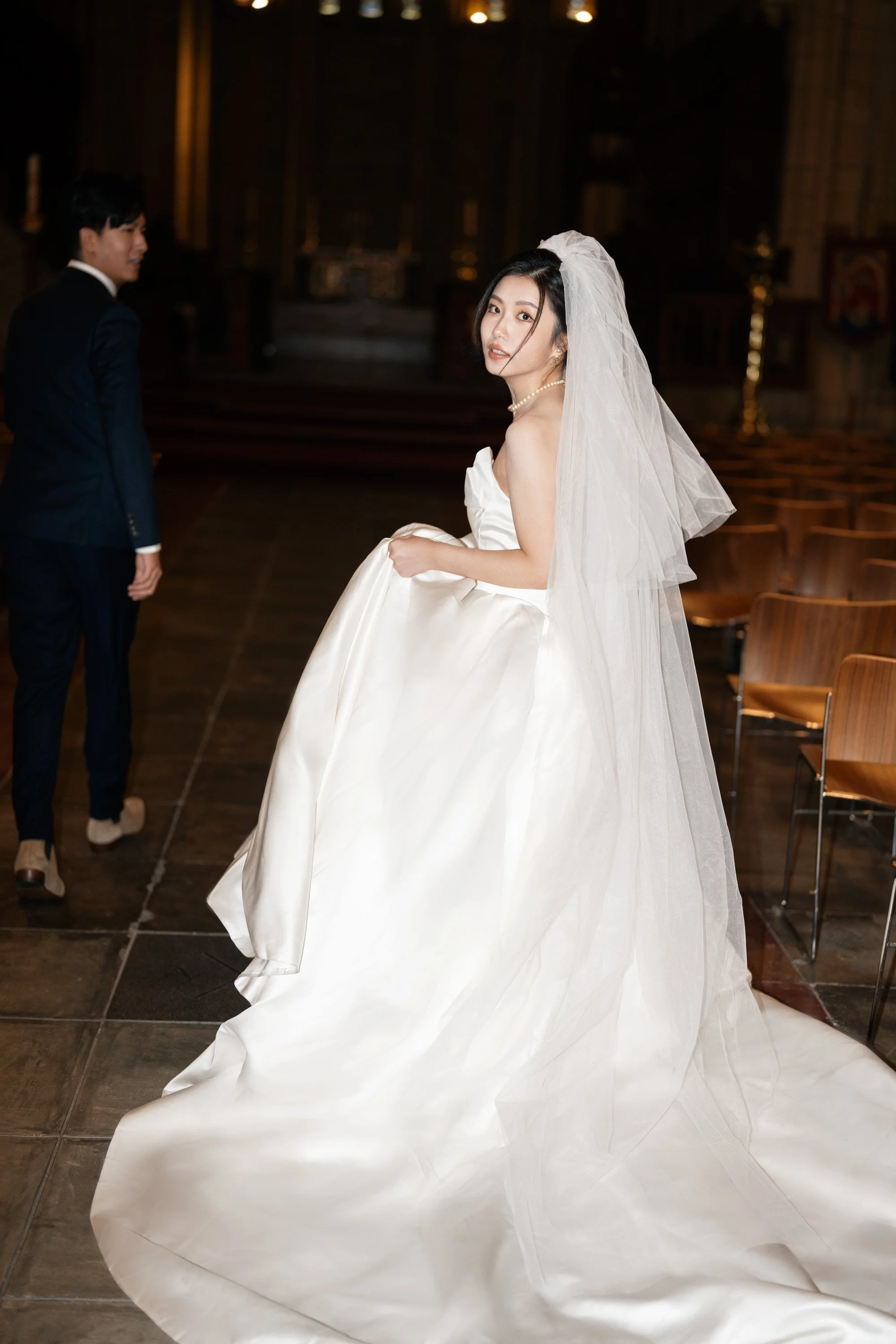bride Cassie holding up her dress walking and look back to the Brisbane wedding photographer Whistler in St John's Cathedral in Brisbane
