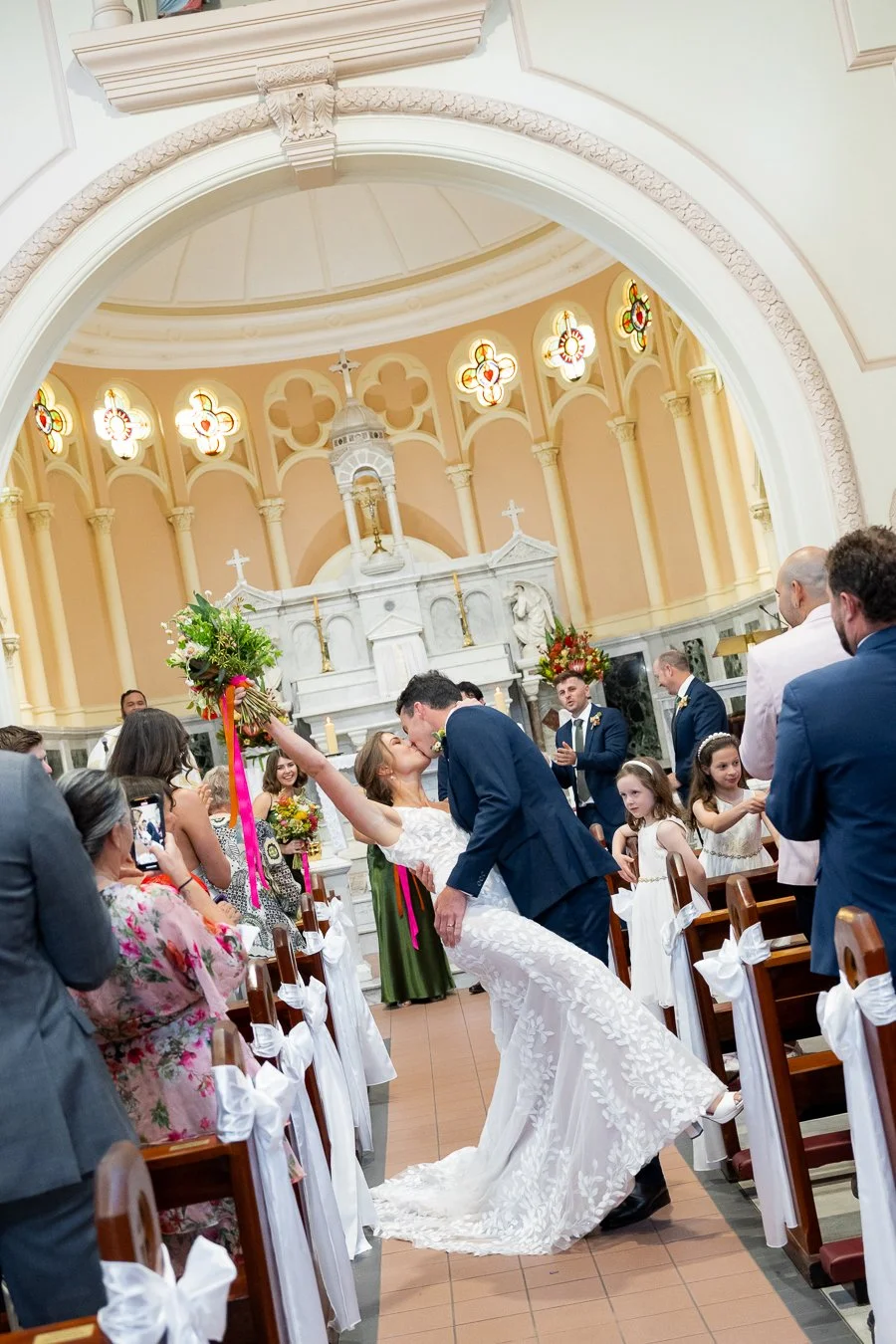 bride and groom kissing in the middle of aisle after ceremony and bride hand up to the air