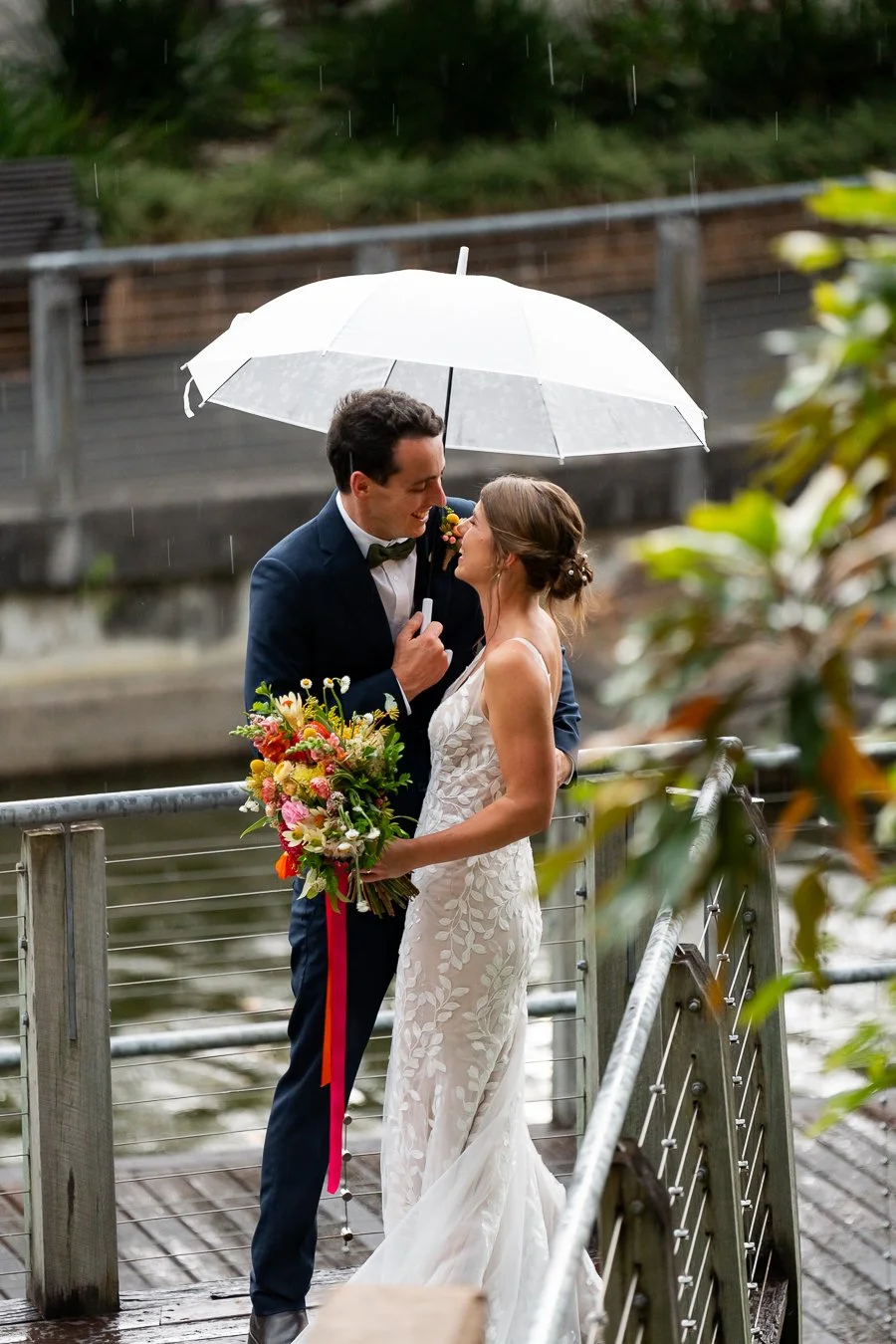 groom Giordan holding bride Sonya's waist and they both laughing to each other in a raining day