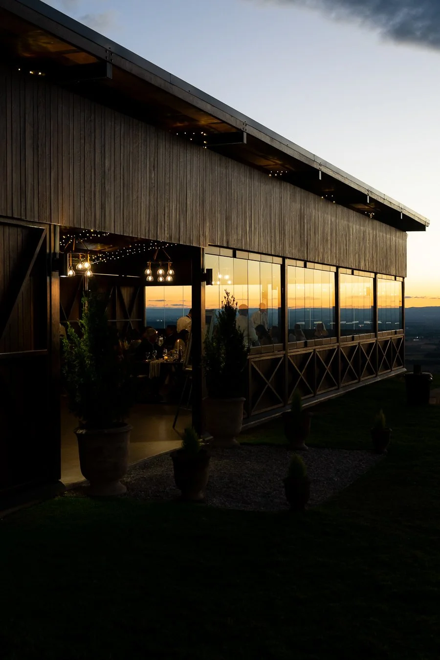 During blue hour, Whistler stood outside, looking through the glass of the house as the warm interior lights glowed inside.