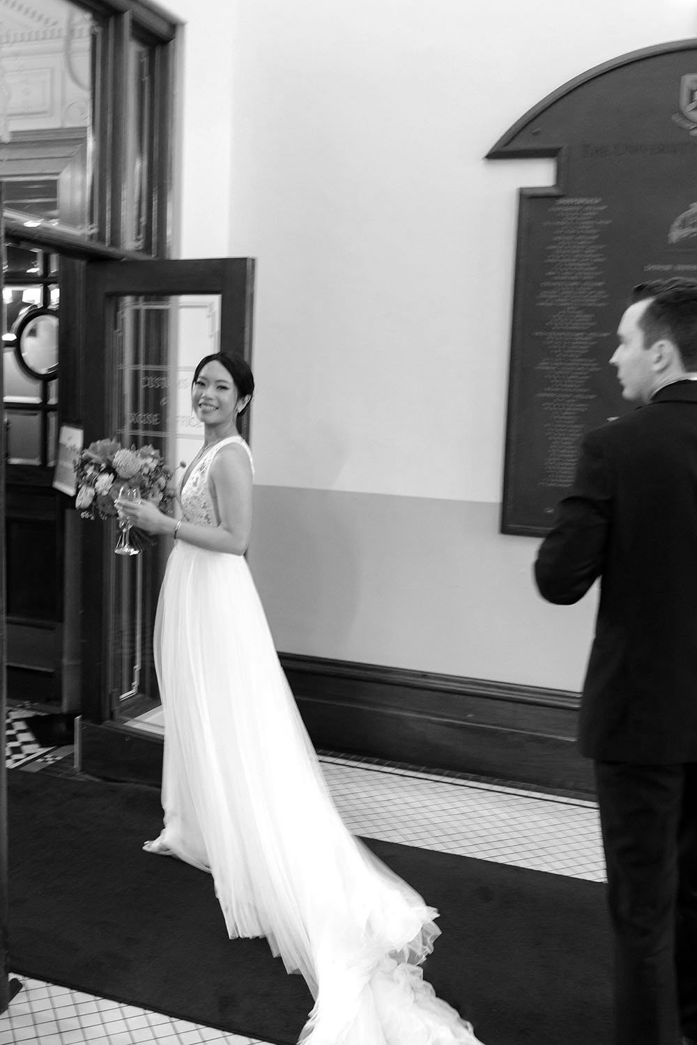 bride Nori look back to the camera and groom Cliffe walking behind her