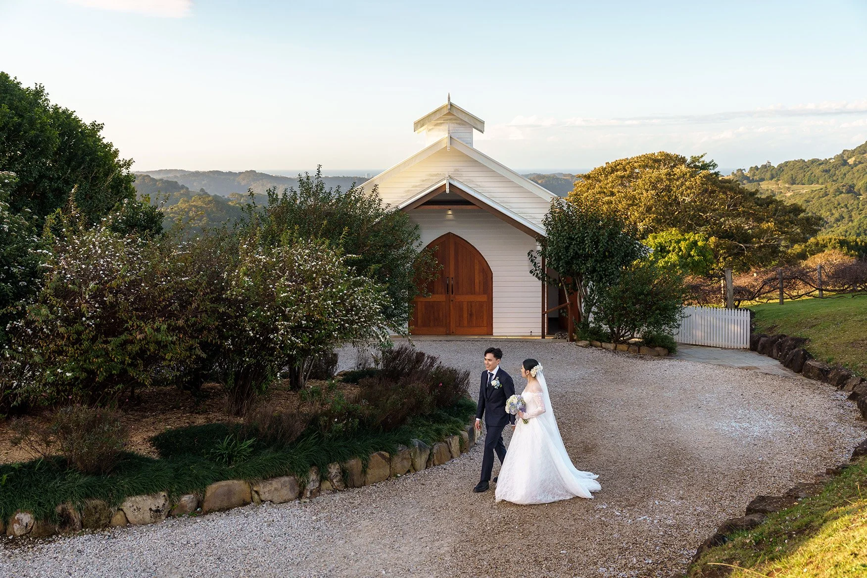 Michael and Lisa holding hands walking in front  of white chapel