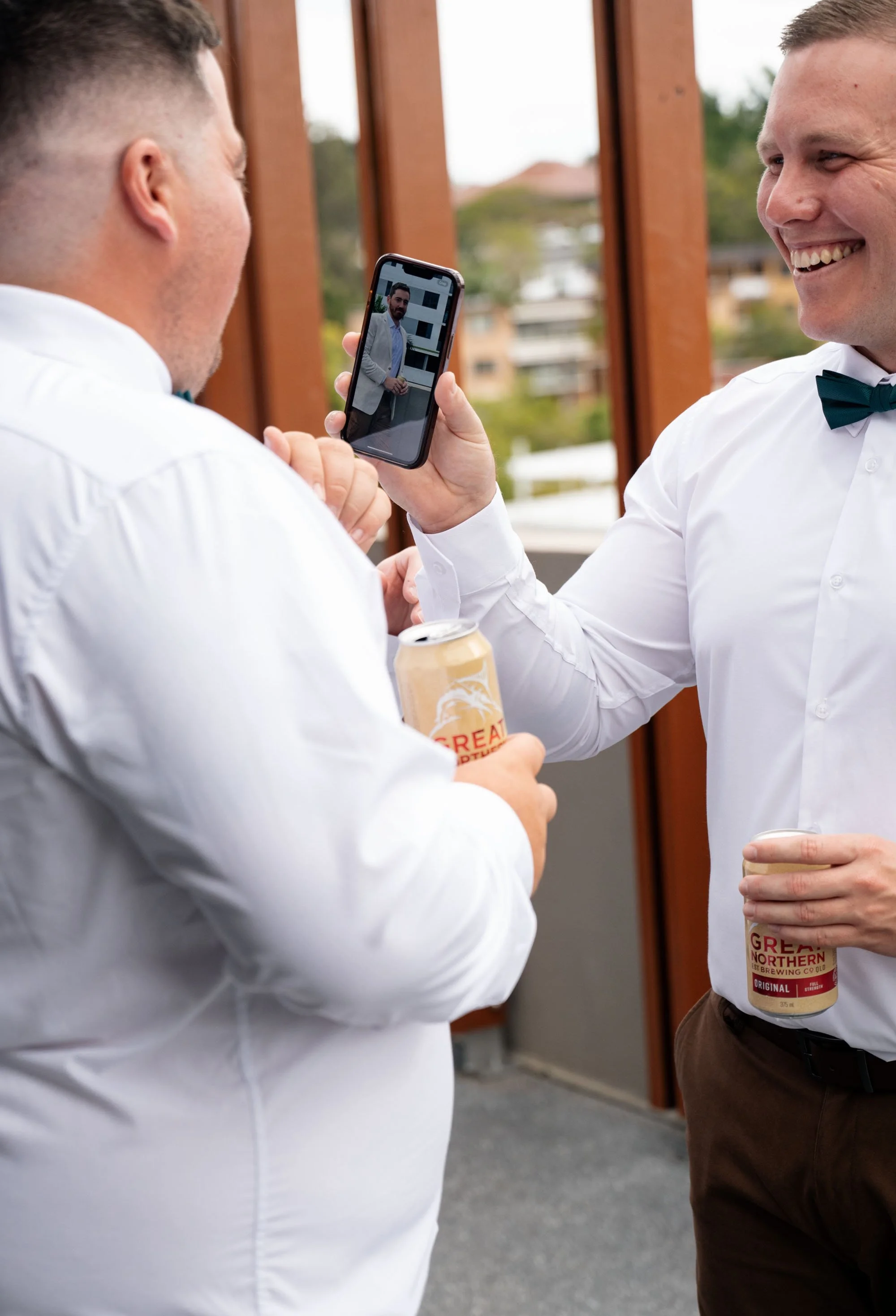 iPhone screen displaying an image of groom Thomas, capturing a moment of him from a unique perspective during the wedding day