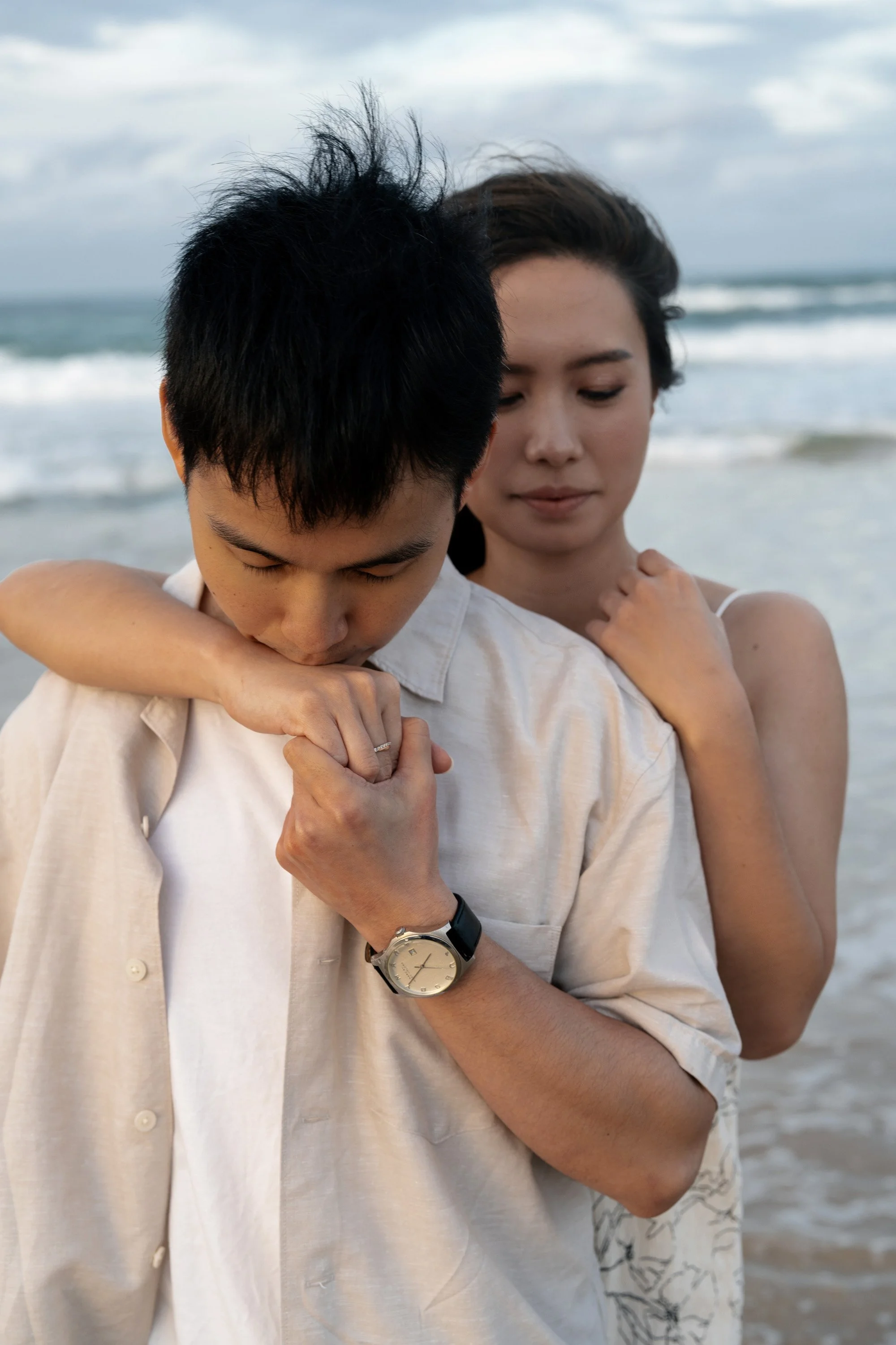Paul kissing Krystel's hand, and she stand behind him in Currumbin Rock, Brisbane engagement photography