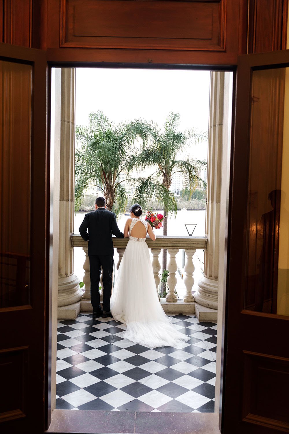 bride Nori and groom Cliffe look down form the balcony to their friends