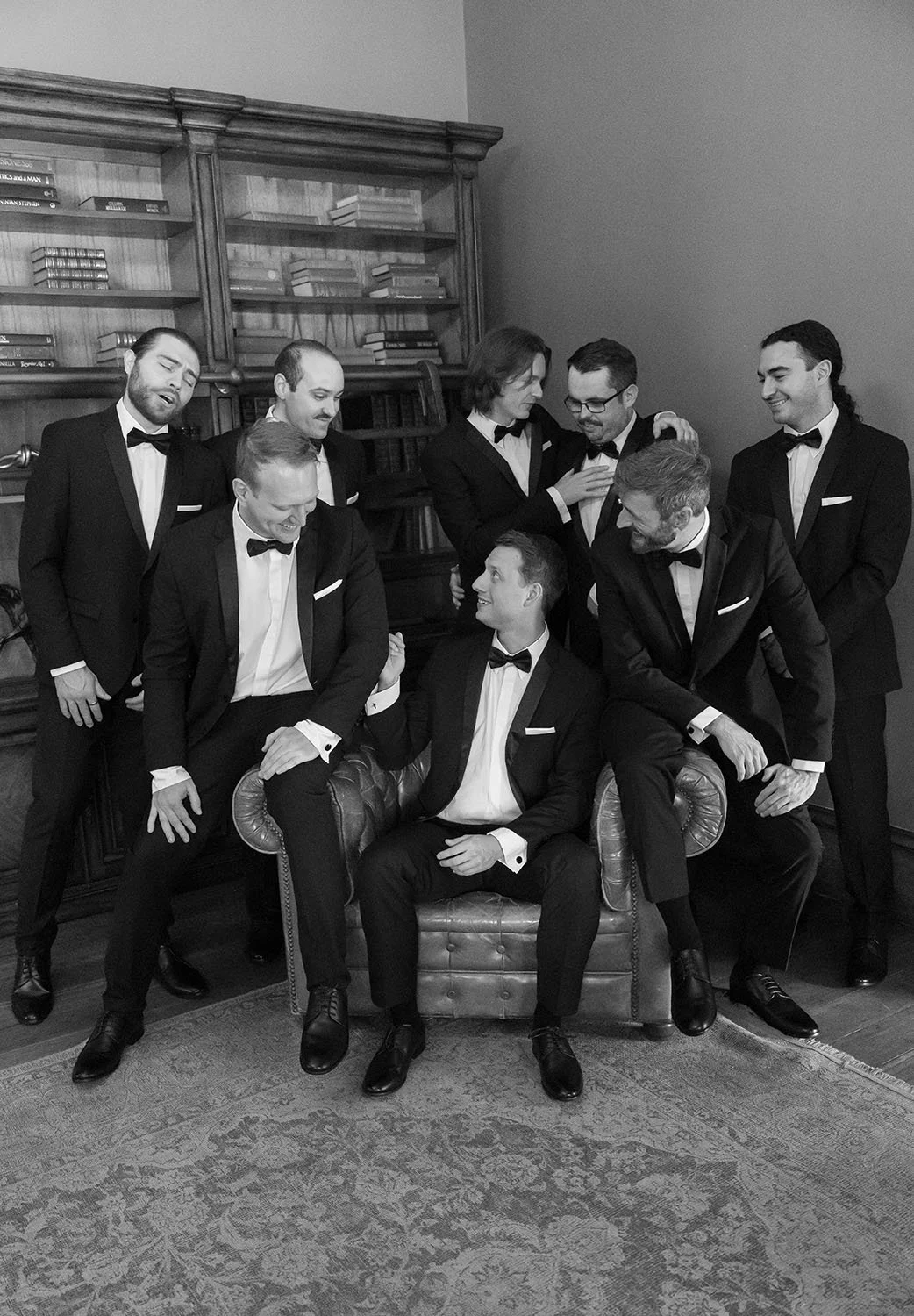 Morgan sitting on a sofa and his groomsmen standing around his laughing together