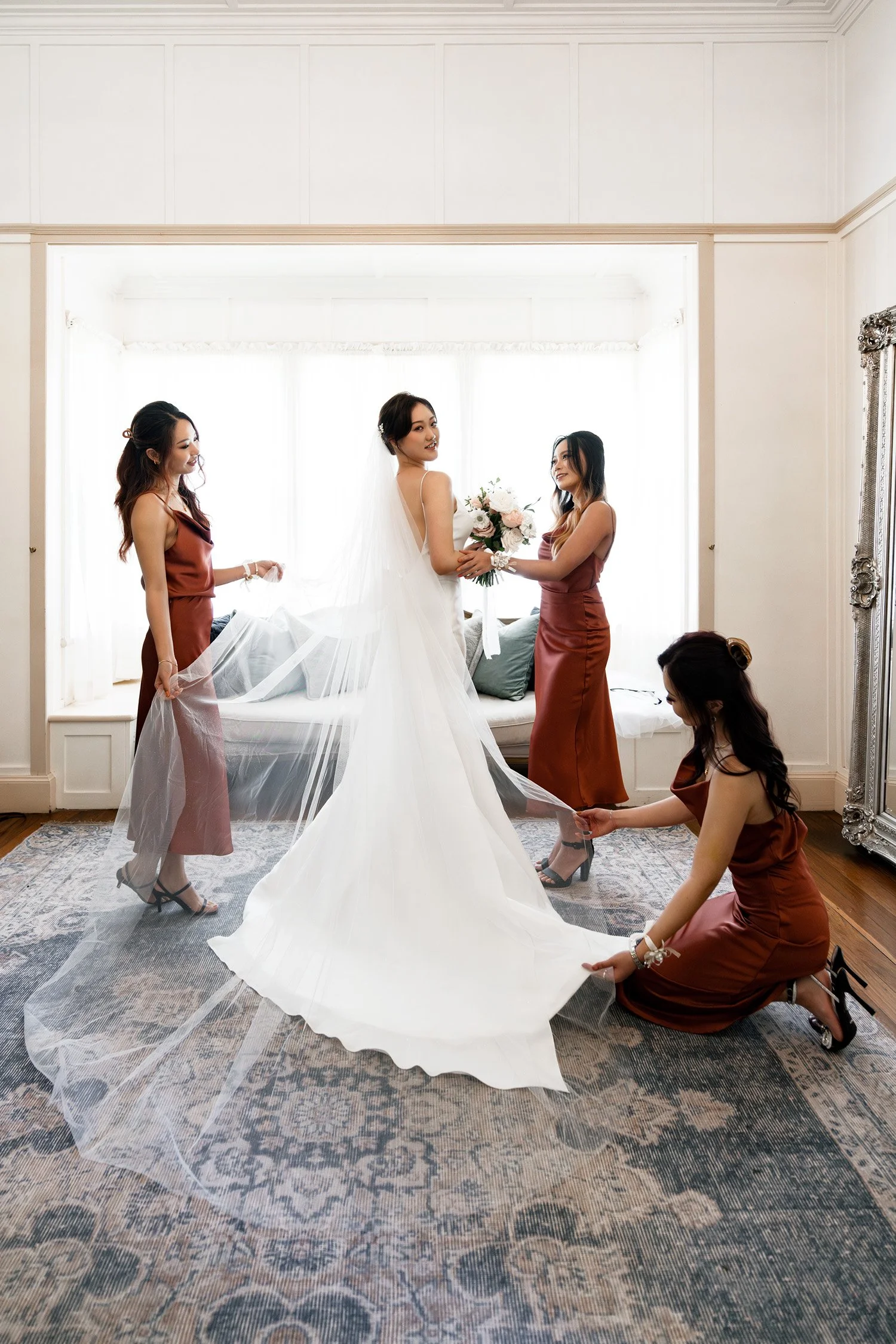 bride look at the wedding Brisbane photographer Whistler, made of honour hold her arm look at her, two bride mates holding her veil