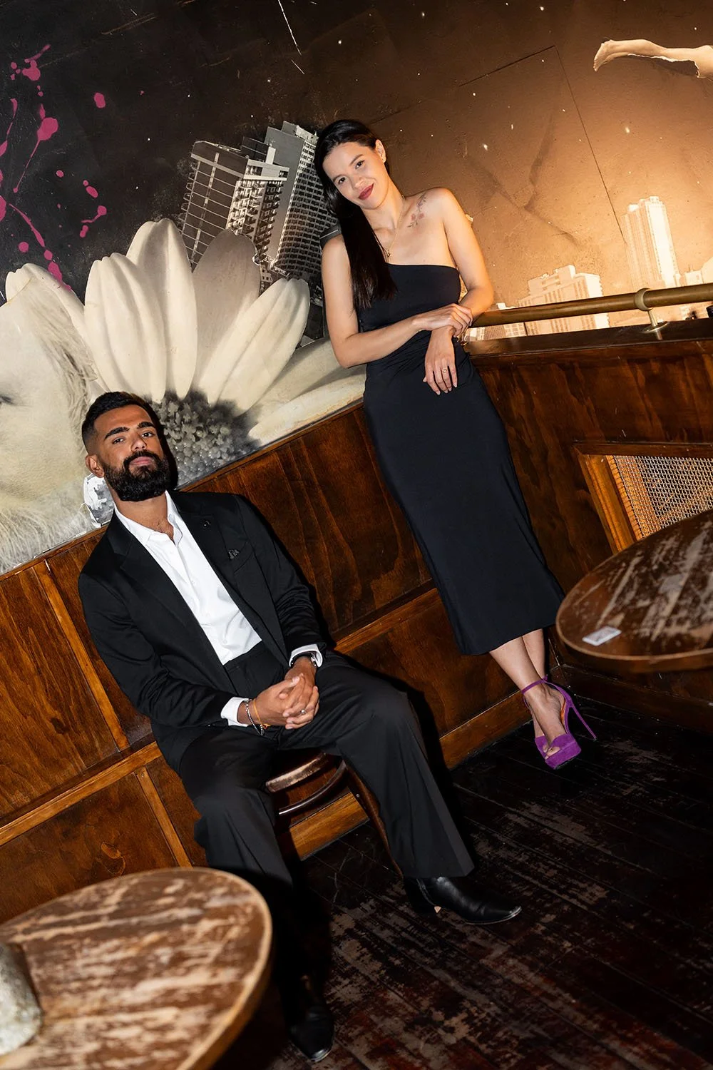 Jasmin leaning on a arm rest and Jay sitting on a chair as they both look at the photographer Whistler