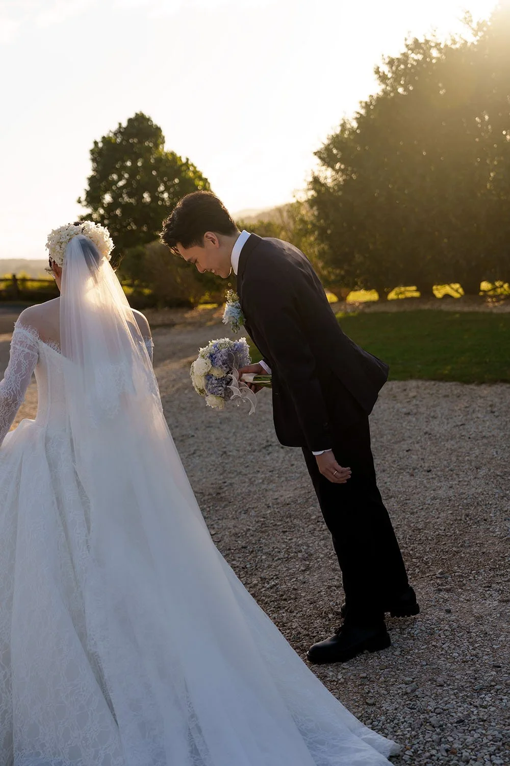 Michael look down when holding Lisa's flower while Lisa adjusting her wedding dress