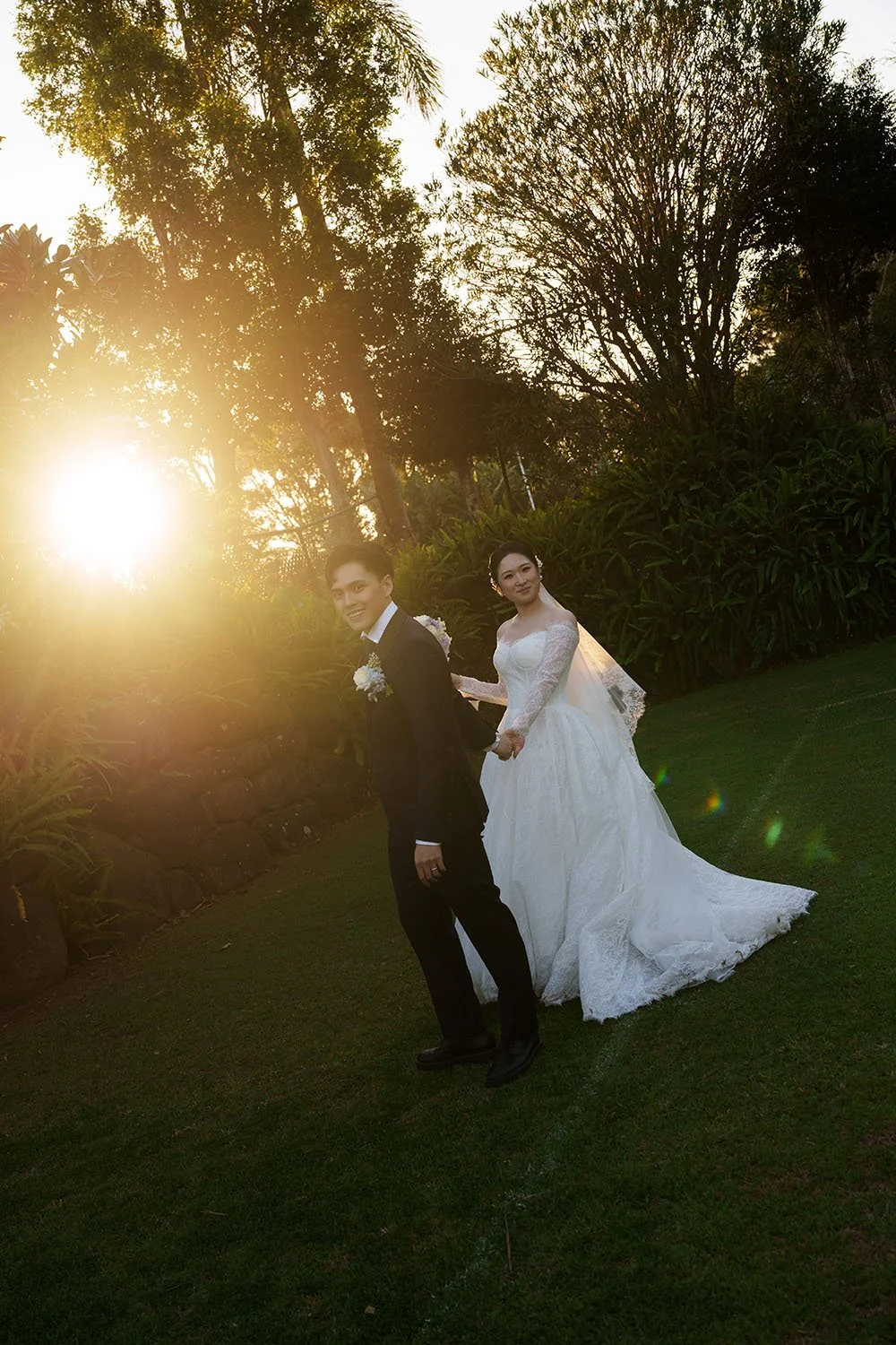 Michael leading Lisa walking with bother look at the Brisbane wedding photographer Whistler Li with sun behind them