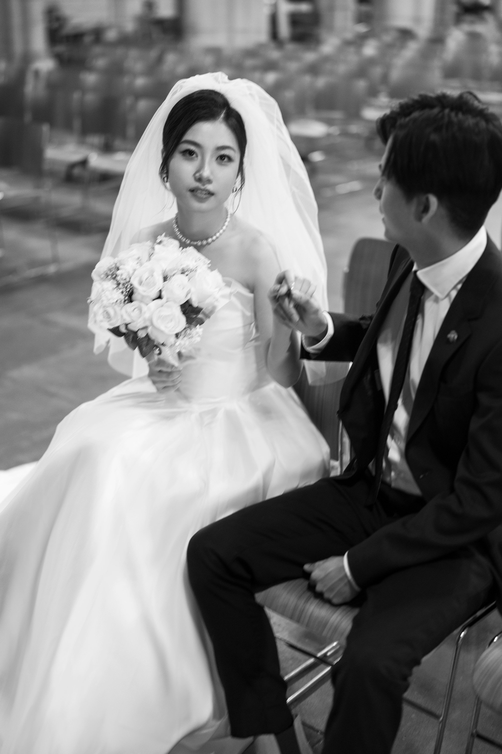 groom Leo holding bride's hand when she look at the camera in black and whit colour, How much does a Brisbane wedding photographer cost