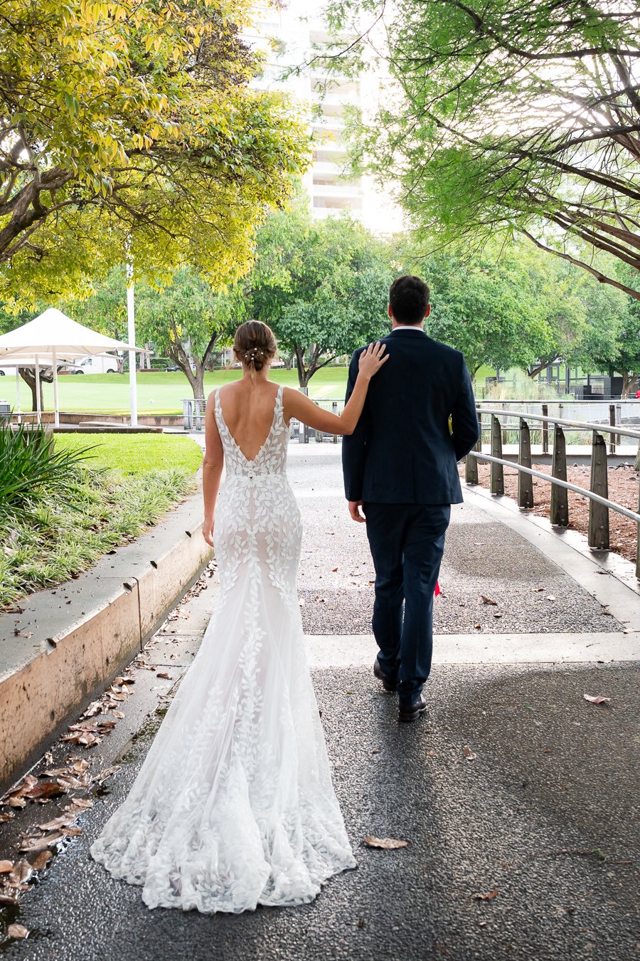 bride Sonya hand on groom's shoulder and they both walk away from the camera