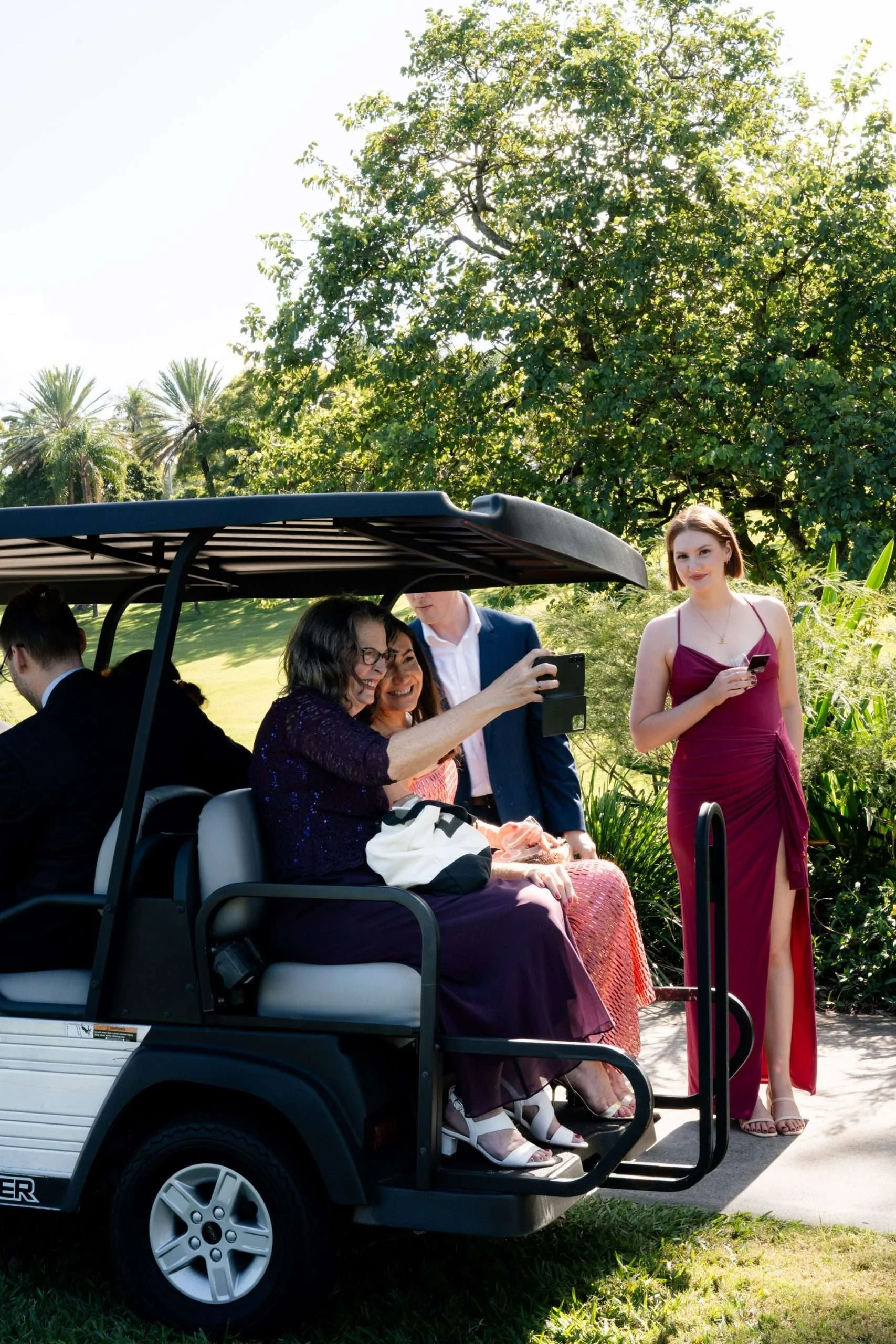 bride and groom's mum both taking photo for them when they sitting on a golf car