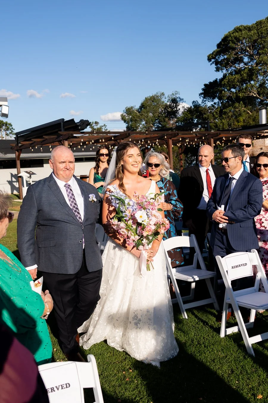 bride Chiarra walking to her father and both look to the front