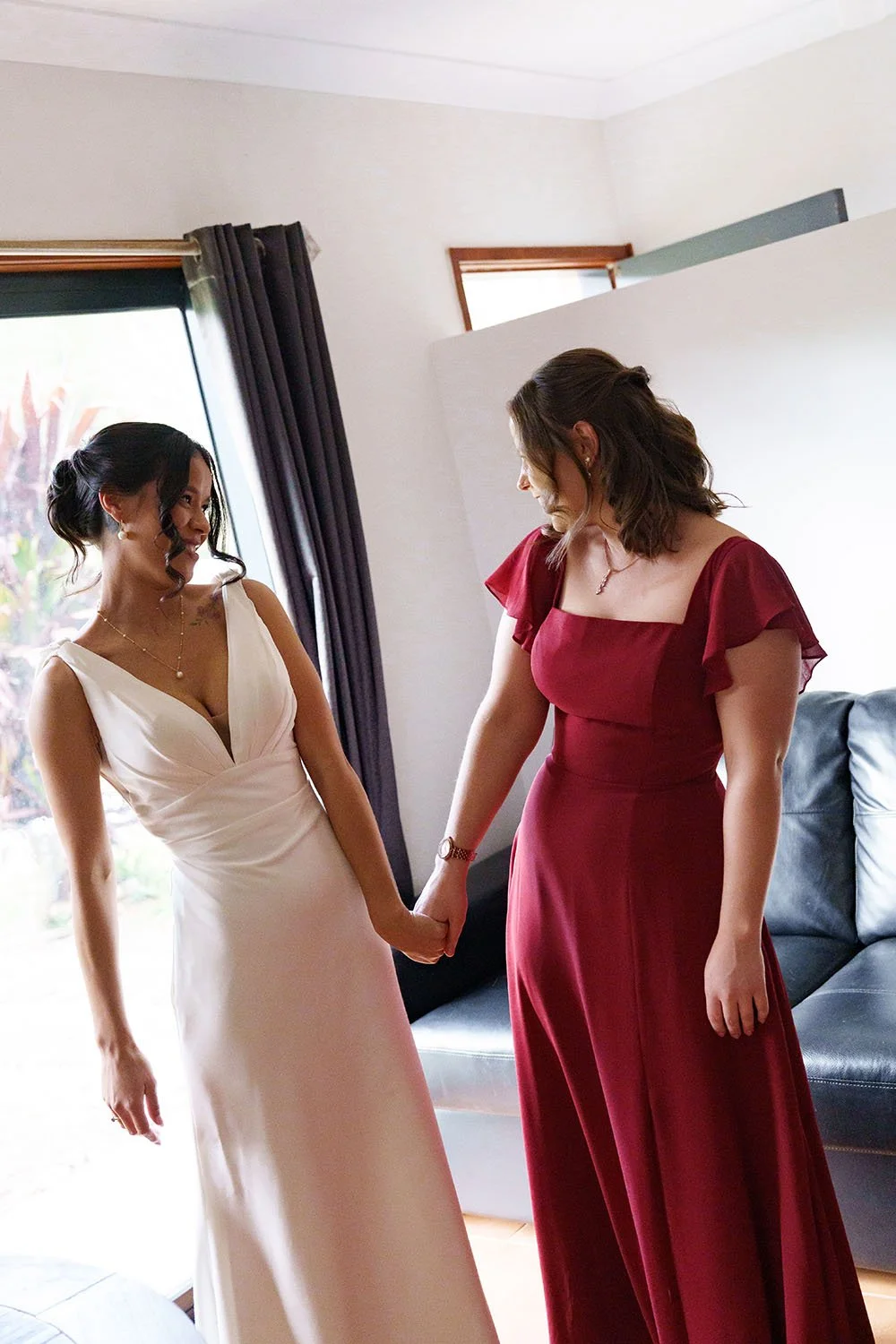 Jasmin and her maid of honour hands holding look at each other with smell