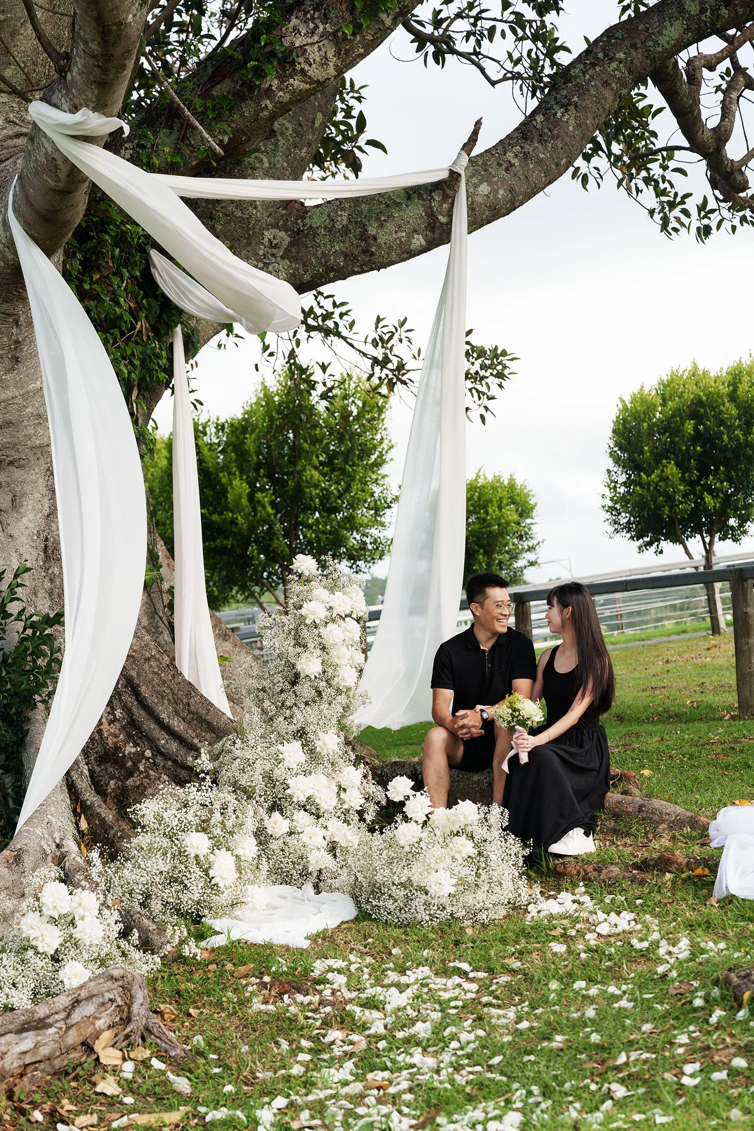 Brain and Rennie sit side by side look at each other with flower in front of them
