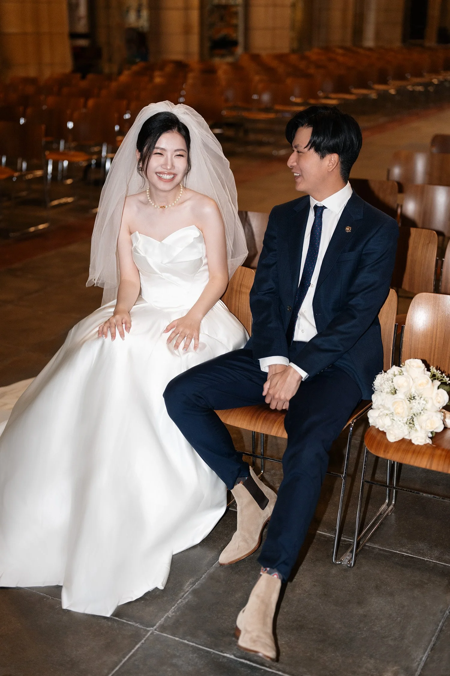 Bride and groom seated on elegant chairs inside St John's Cathedral in Brisbane, captured by Brisbane wedding photographer Whistler. The grandeur of the cathedral’s architecture serves as a stunning backdrop, highlighting the couple's serene and inti