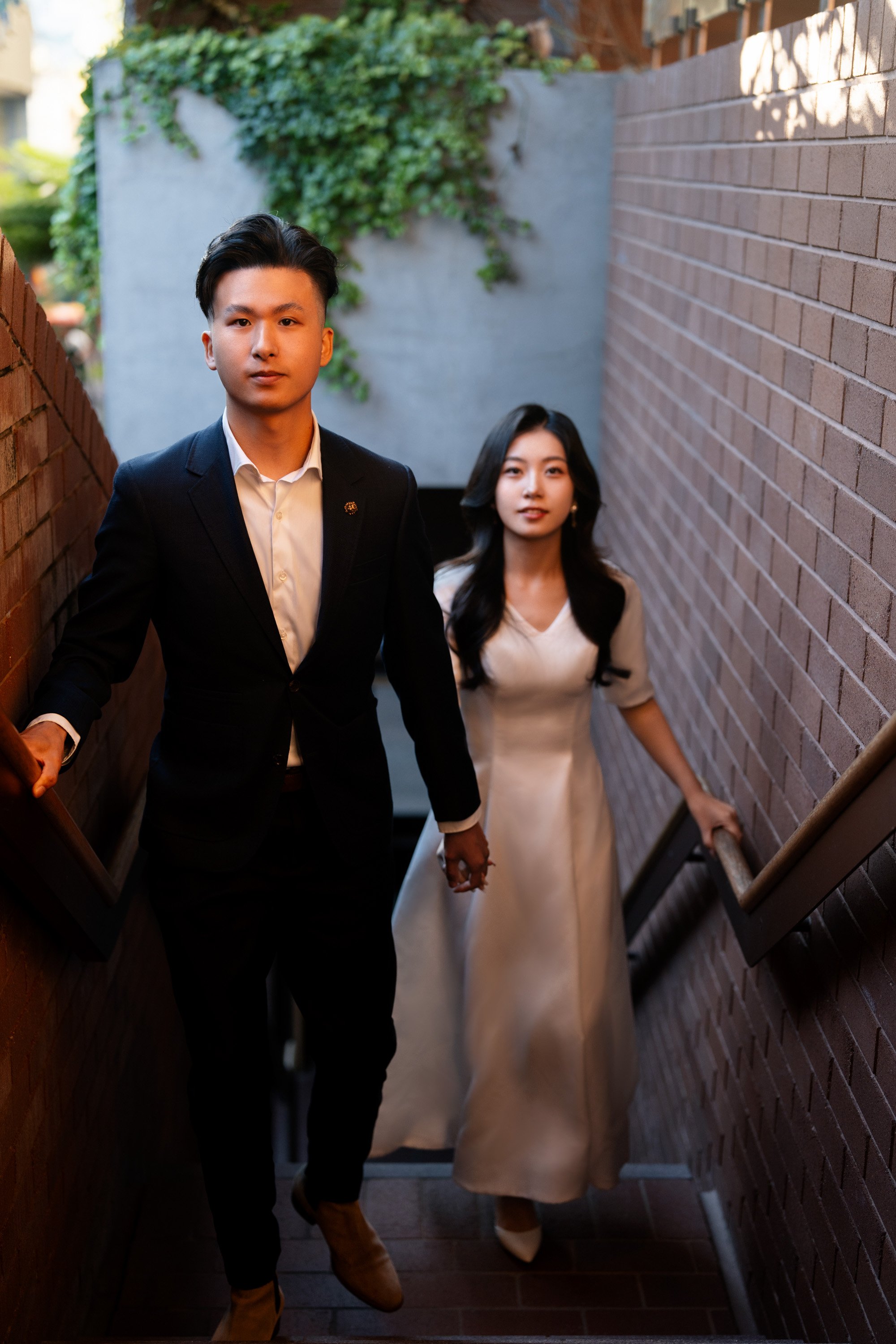 bride and groom holding hands walking up to the stairs when they both look at the Brisbane engagement photographer