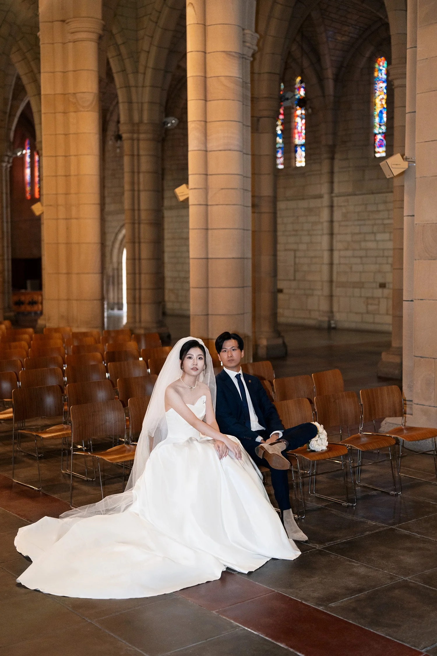 bride and groom sitting on the chair and both look at the Brisbane wedding photographer Whistler in St John's Cathedral in Brisbane