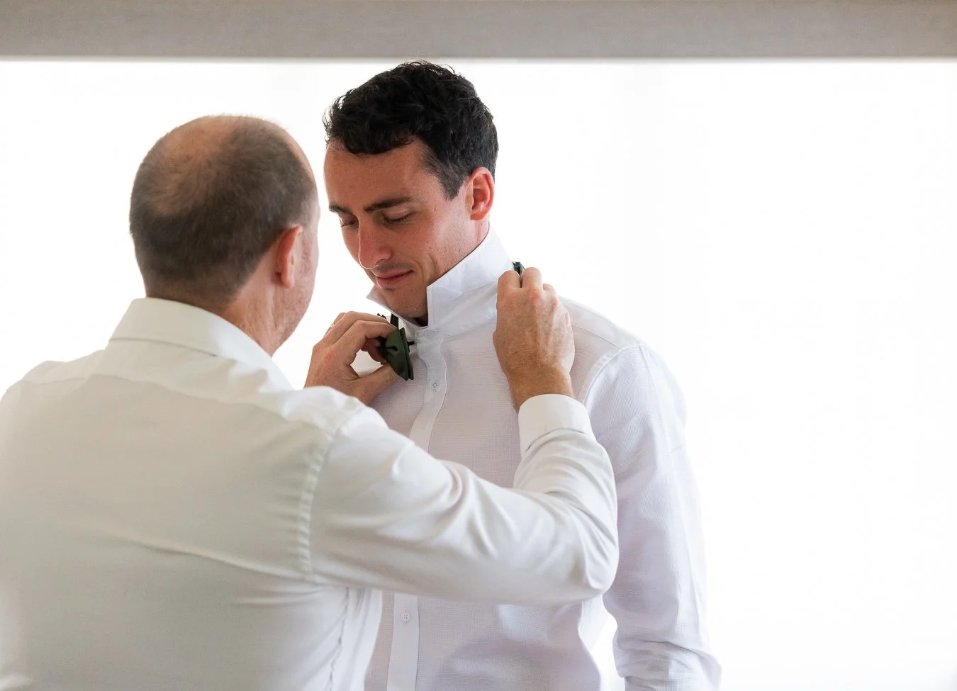 best man helped the groom put on his green bow tie