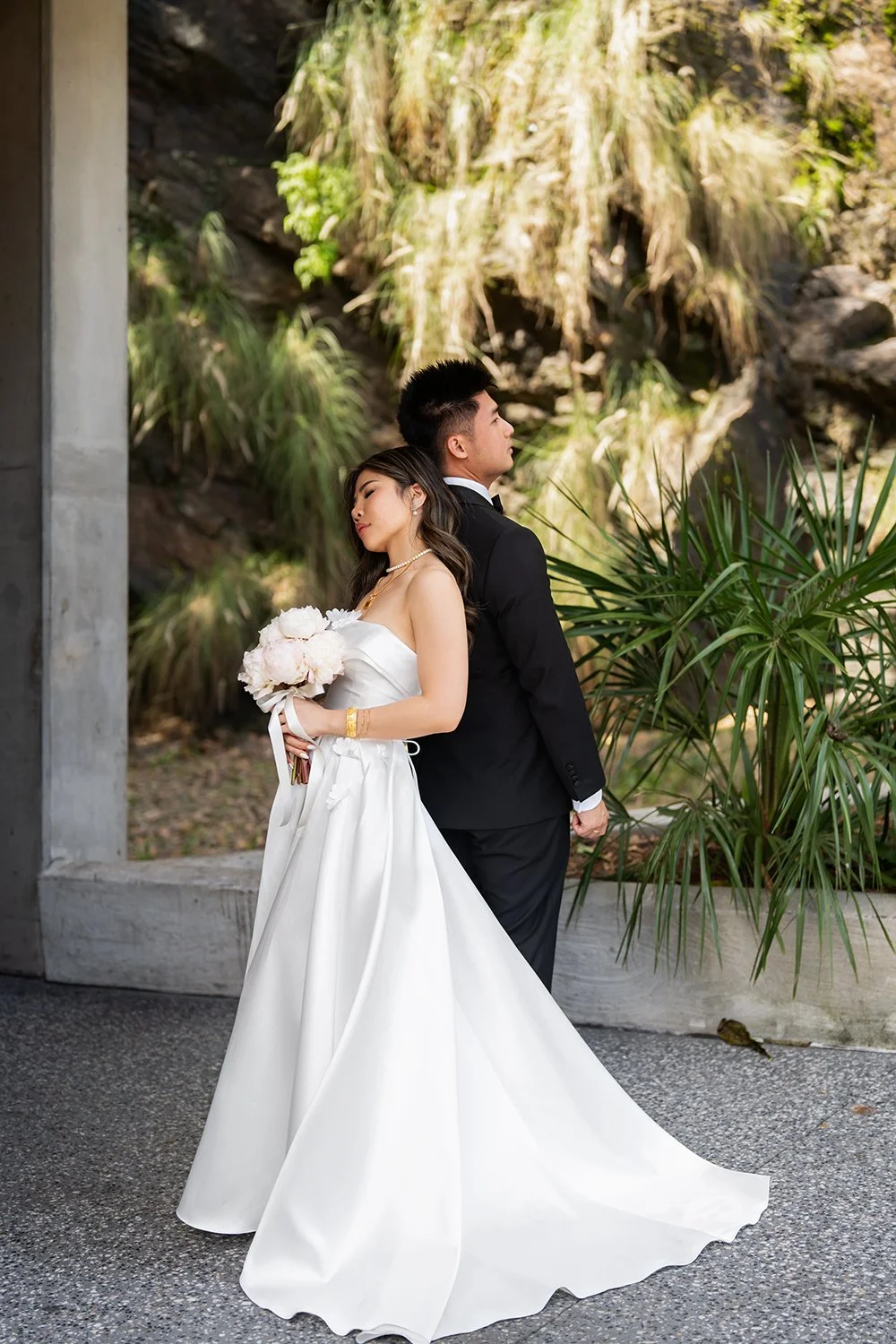 Bride Tiffy leaning back against the groom kai, eyes closed in a moment of relaxation and trust. The groom supports her gently, creating a serene and intimate scene, highlighting the deep connection between them in this peaceful, romantic moment.