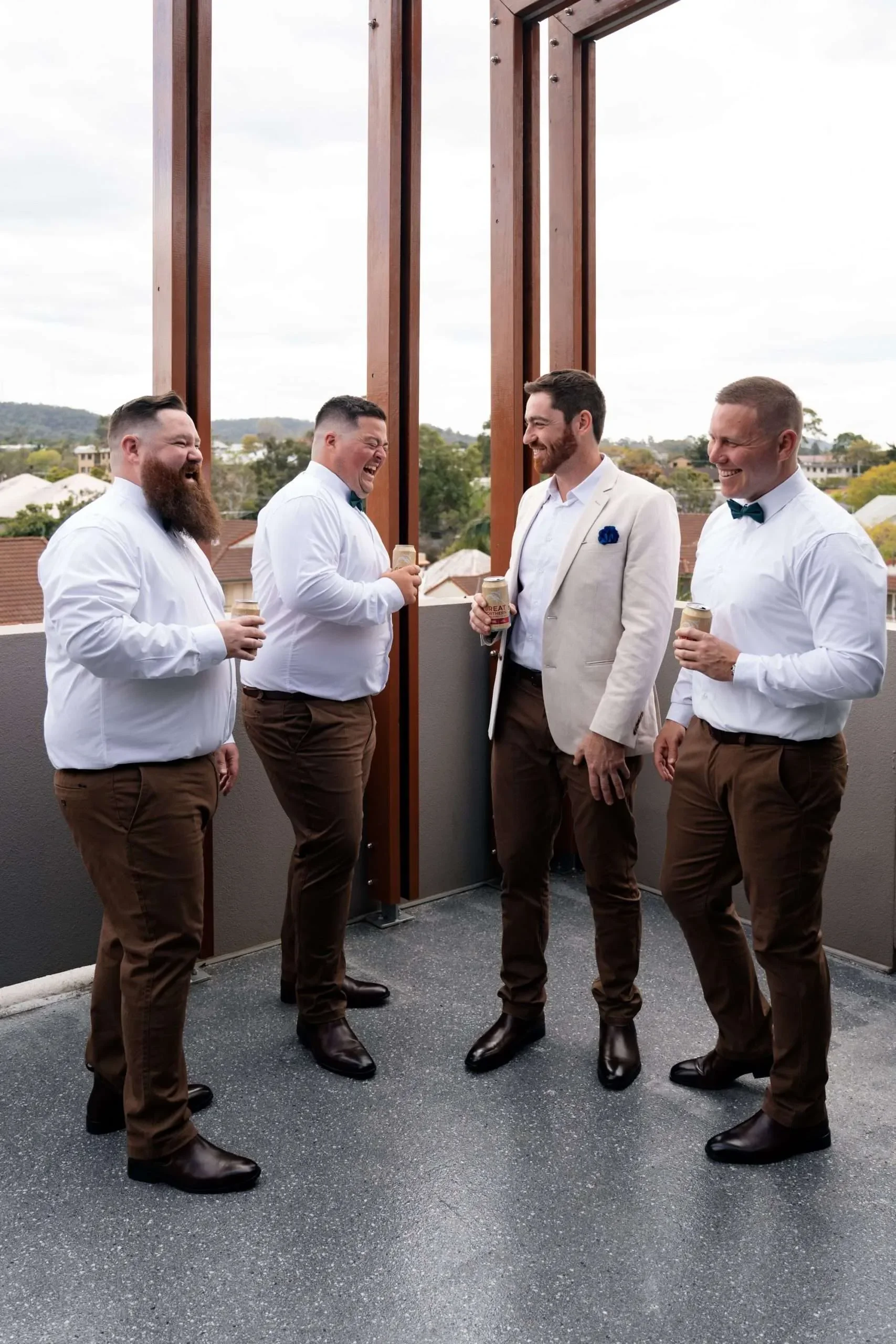 Thomas and his groomsmen laughing together while holding beers, enjoying a fun and lighthearted moment before the wedding ceremony