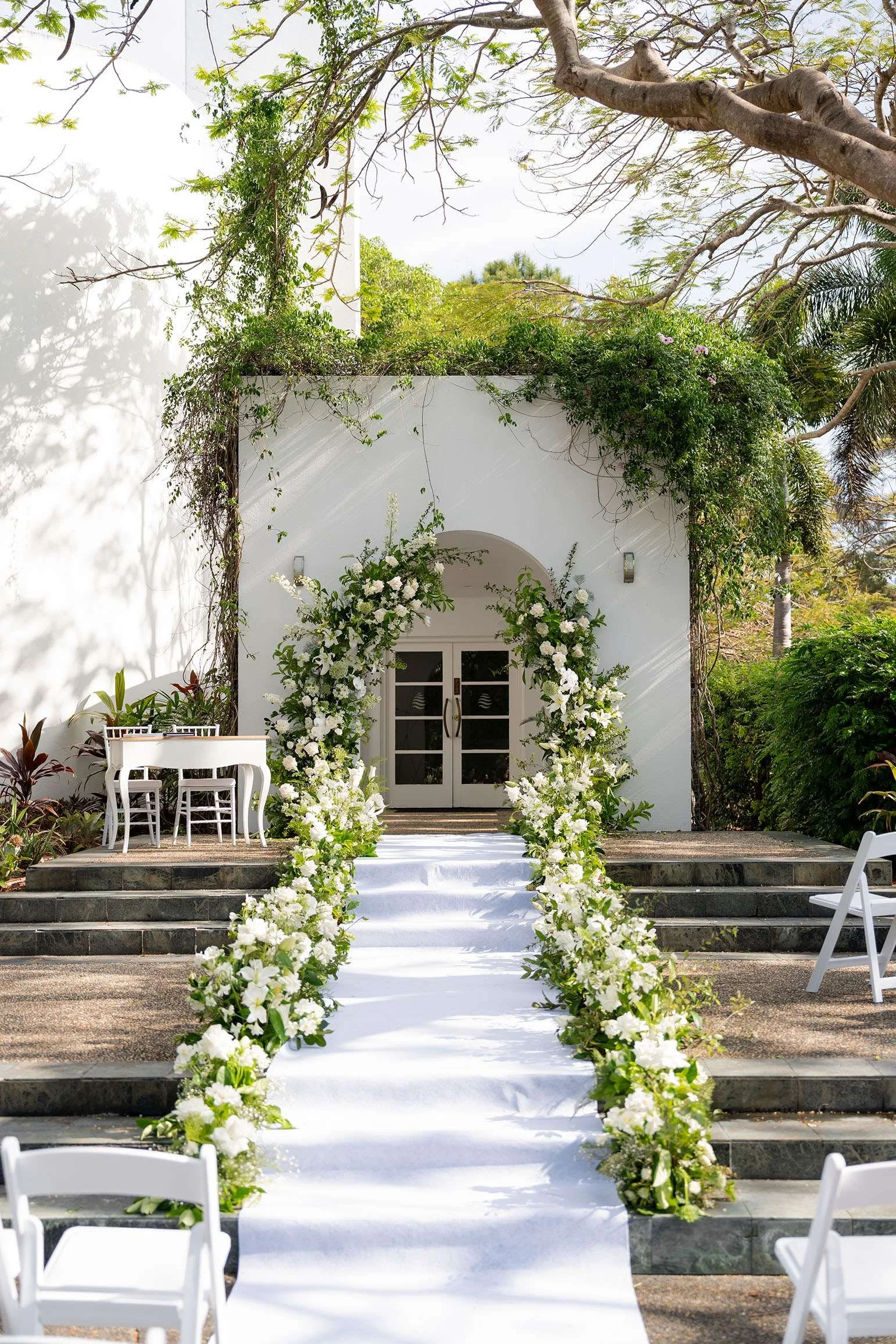 flower arch at the Wendy and Alex wedding ceremony, surrounded by flowers, the stairs are lined with flowers on both sides